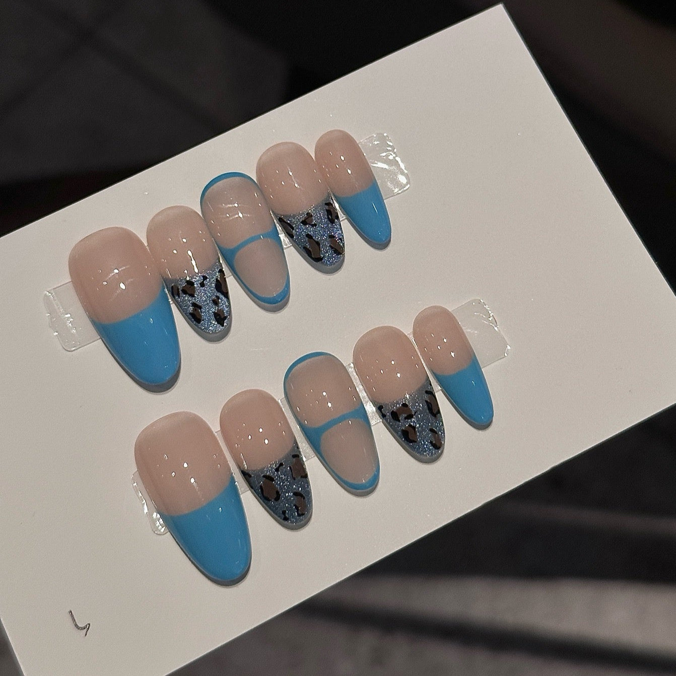 Unleash your wild side with Blue Safari Chic Press-On Nails, a bold fusion of vibrant turquoise French tips and glittery leopard print accents. This playful set features a sophisticated nude base enhanced with metallic blue details for a striking, modern look. With a glossy finish and stylish almond shape, Blue Safari Chic brings a touch of adventurous elegance to your fingertips.