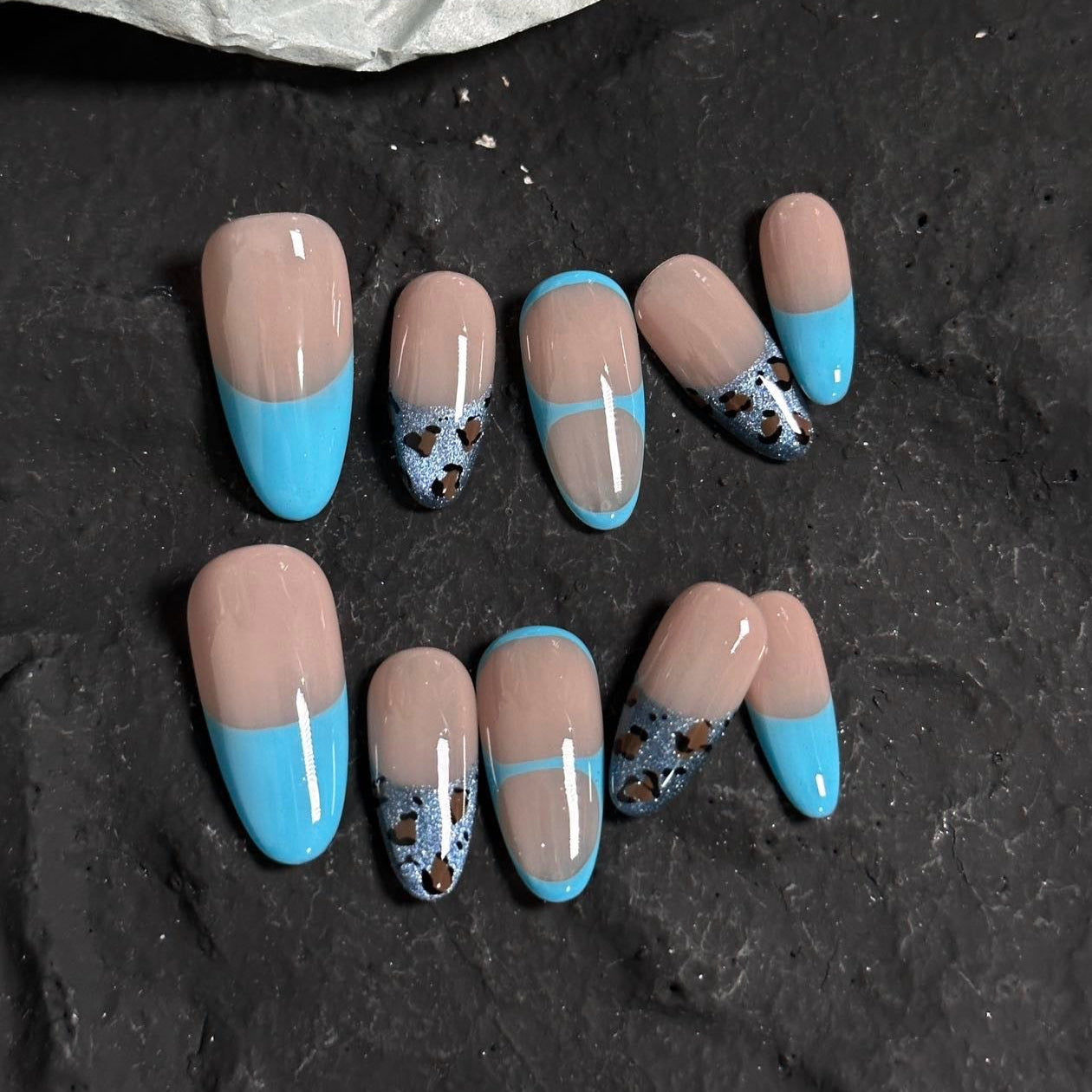 Unleash your wild side with Blue Safari Chic Press-On Nails, a bold fusion of vibrant turquoise French tips and glittery leopard print accents. This playful set features a sophisticated nude base enhanced with metallic blue details for a striking, modern look. With a glossy finish and stylish almond shape, Blue Safari Chic brings a touch of adventurous elegance to your fingertips.