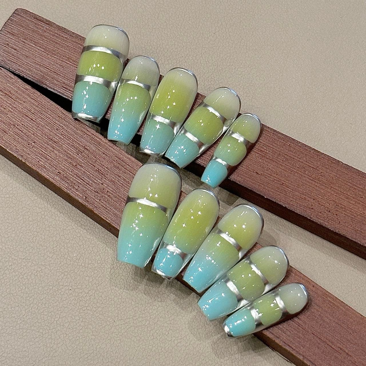Buzz Lightyear Press-On Nails bring a cosmic-inspired twist to your manicure with a sleek, futuristic gradient of neon green, sky blue, and silver. Reminiscent of space gear and sci-fi aesthetics, this design merges adventure and modern elegance. The chrome silver bands add a structured, high-tech edge, making these nails perfect for those who love a bold, intergalactic look.