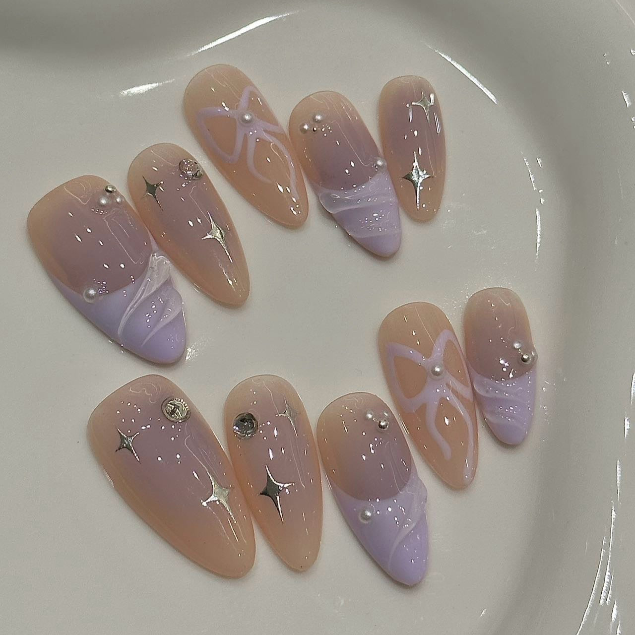 Celestial Blush Press-On Nails embody an ethereal elegance with soft nude tones, delicate lavender accents, and shimmering star details. This set blends dreamy pastels with a celestial aesthetic, perfect for those who adore a soft yet sophisticated nail look.