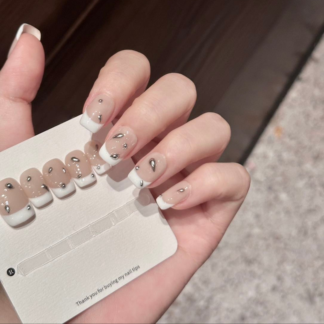 Redefine classic chic with Chrome Drip Elegance Press-On Nails, a modern twist on the iconic French manicure featuring a nude base with crisp white tips and chrome droplet accents. This sophisticated set showcases 3D chrome embellishments that create a bold, futuristic look while maintaining timeless elegance. With a glossy finish and structured short square shape, Chrome Drip Elegance brings a refined yet edgy vibe to your fingertips.