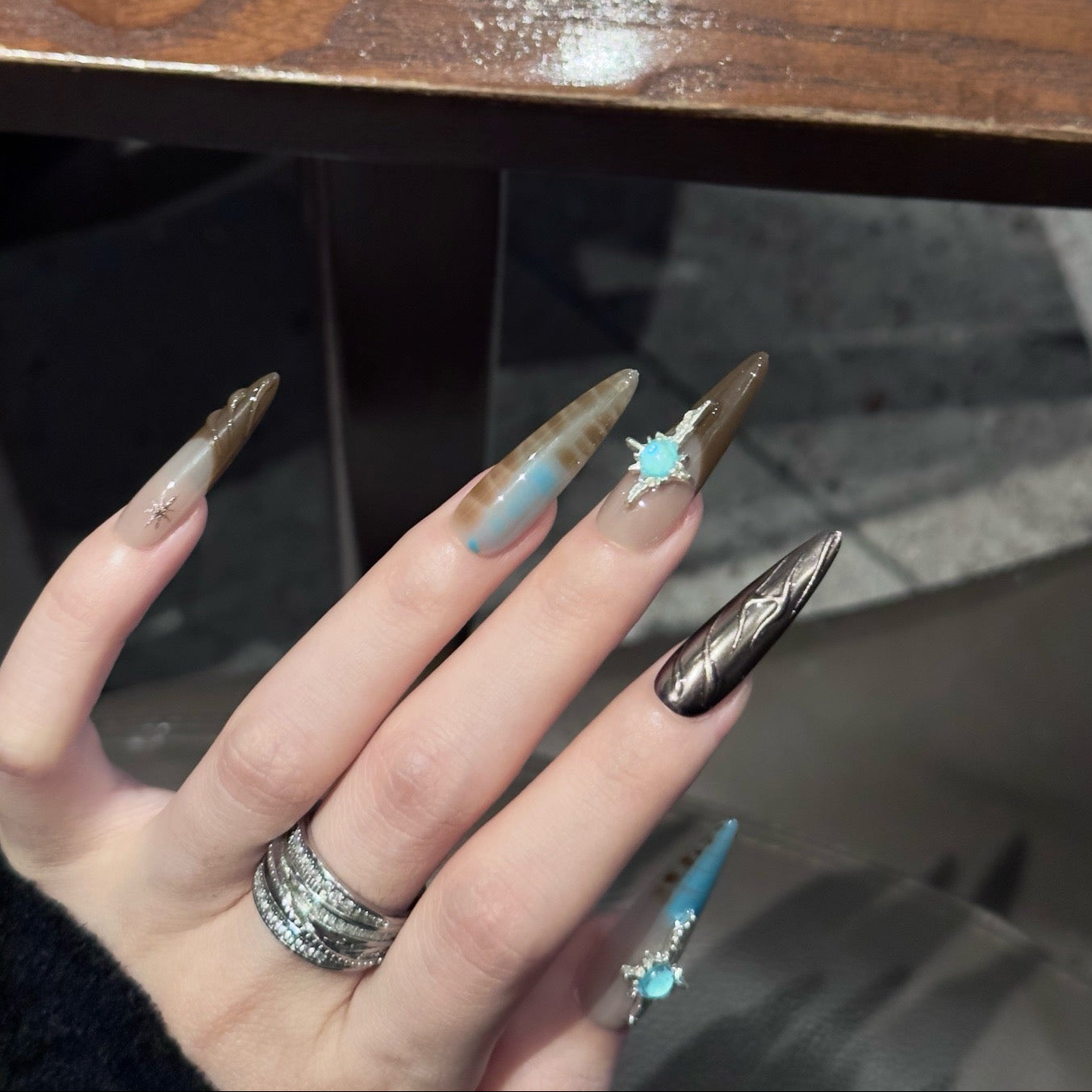 Embrace the mystique of the desert with Desert Dusk Press-On Nails, a stunning blend of earthy browns, sandy taupes, and turquoise accents. This set features intricate feather patterns, metallic bronze details, and opalescent gemstone embellishments, evoking the beauty of a sunlit desert oasis. The glossy finish and elongated stiletto shape add a touch of elegance and drama, perfect for those who love a boho-chic, nature-inspired aesthetic.