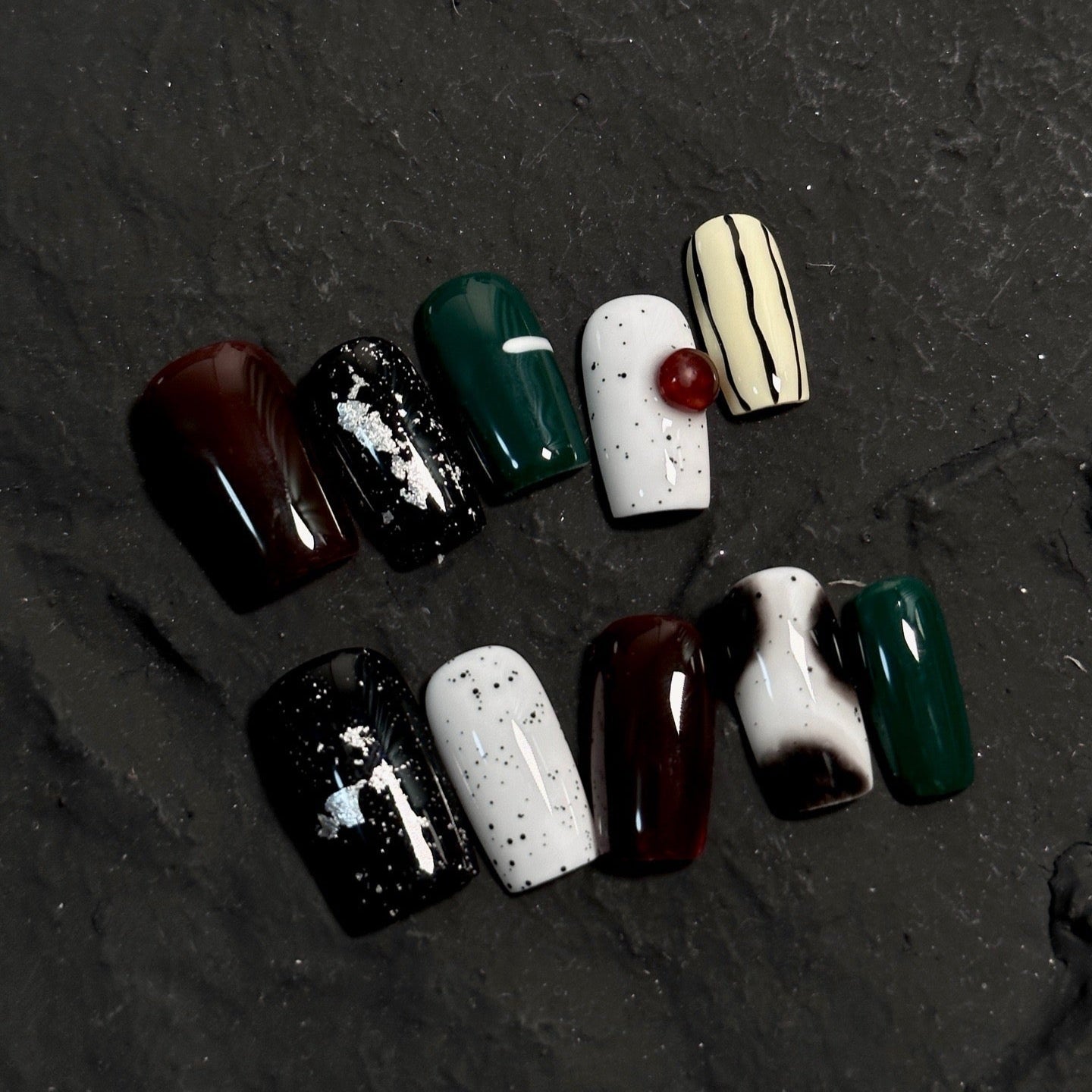 Embrace natural beauty with Earthly Elegance Press-On Nails. These medium square-shaped nails feature a unique ceramic-like texture that adds a sophisticated, artisanal touch. Designed in earthy black and white tones with a striking emerald green accent, they showcase hand-drawn lines and dots for an artistic, organic look.