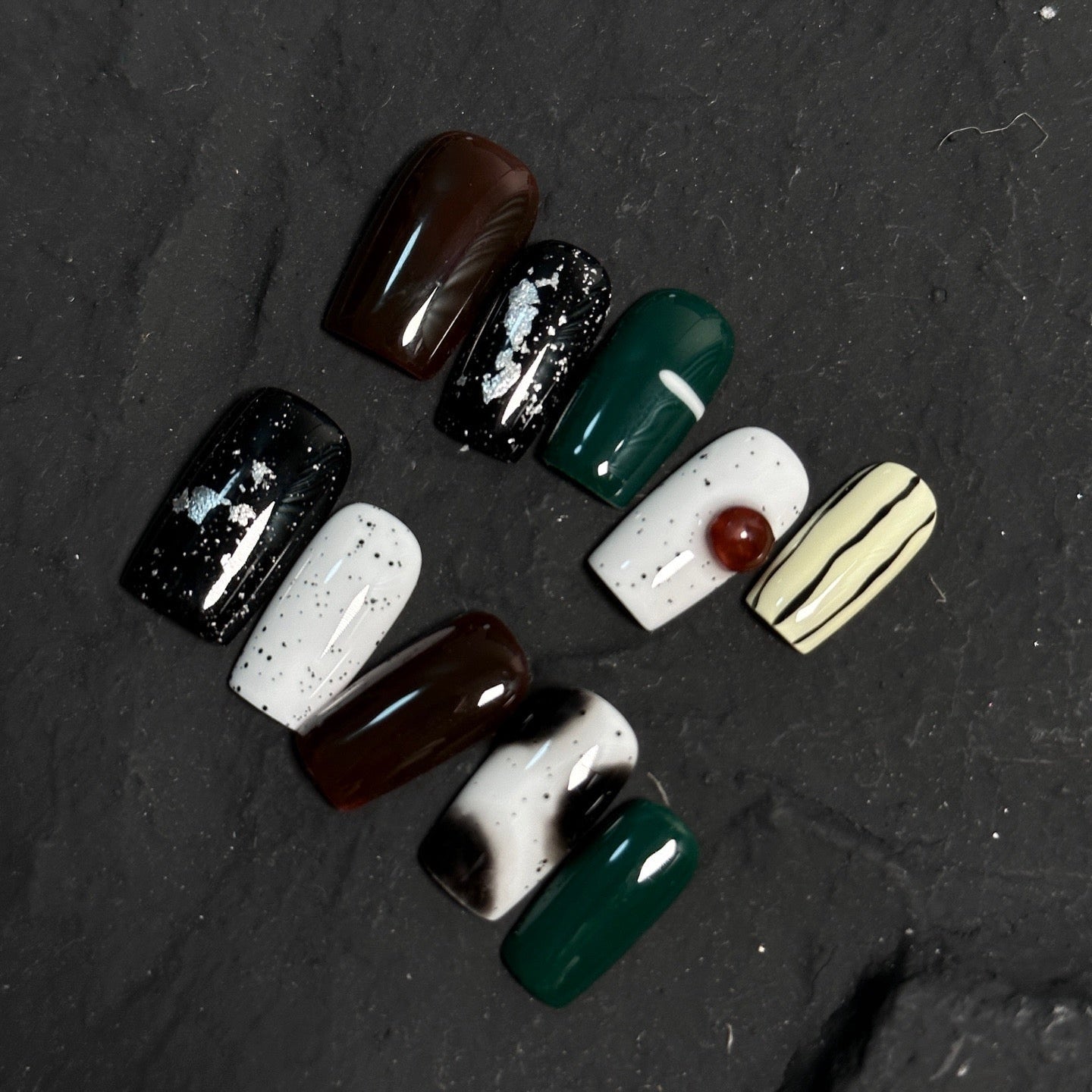 Embrace natural beauty with Earthly Elegance Press-On Nails. These medium square-shaped nails feature a unique ceramic-like texture that adds a sophisticated, artisanal touch. Designed in earthy black and white tones with a striking emerald green accent, they showcase hand-drawn lines and dots for an artistic, organic look.