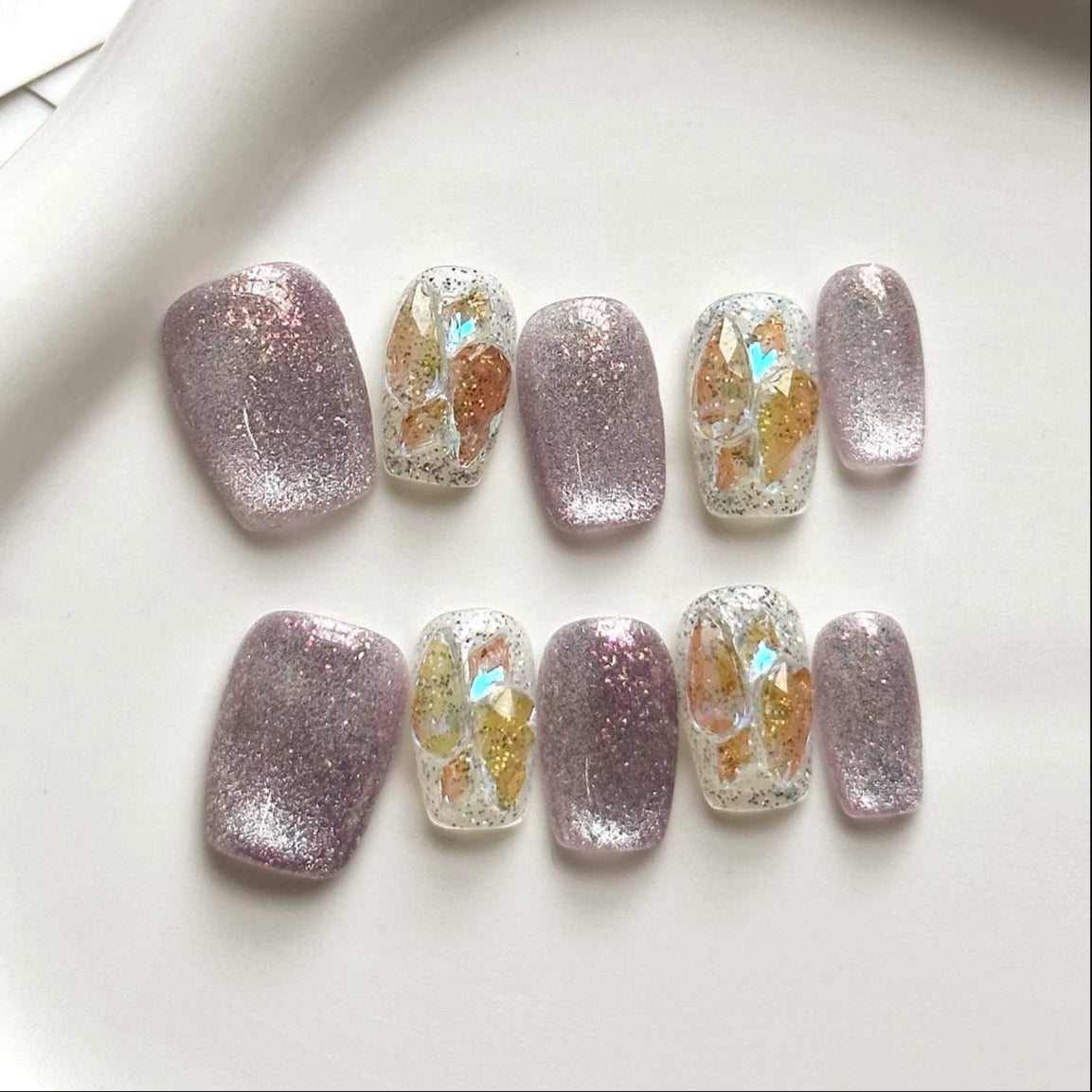 Step into a magical realm with Fairy Dust Press-On Nails, a whimsical blend of shimmering lavender glitter and iridescent gold leaf accents. This enchanting set features a sparkling, ethereal glow that catches the light beautifully, reminiscent of fairy wings and enchanted forests. Paired with a glossy finish and elegant square shape, Fairy Dust brings a touch of fantasy and charm to your style.