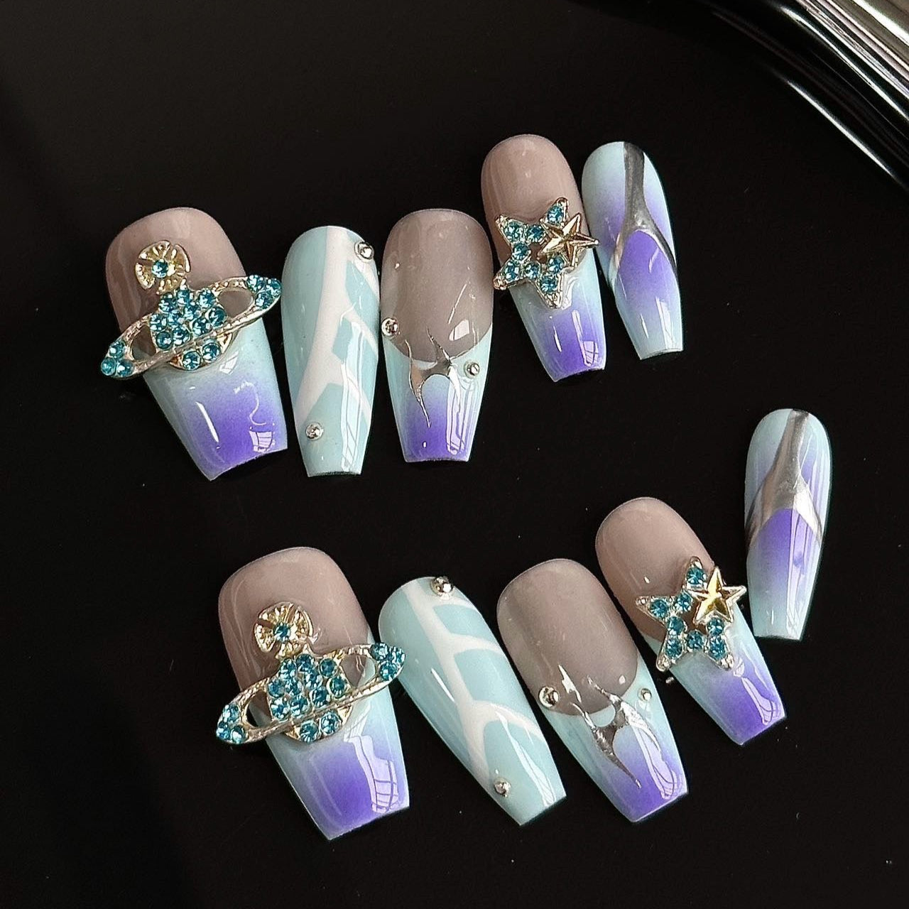 Galactic Glam Press-On Nails take you on a cosmic journey with their mesmerizing ombré of blue to lavender hues, paired with metallic accents and sparkling crystal charms. The planetary motifs and star-studded embellishments create a celestial vibe that’s perfect for the dreamer and stargazer at heart.