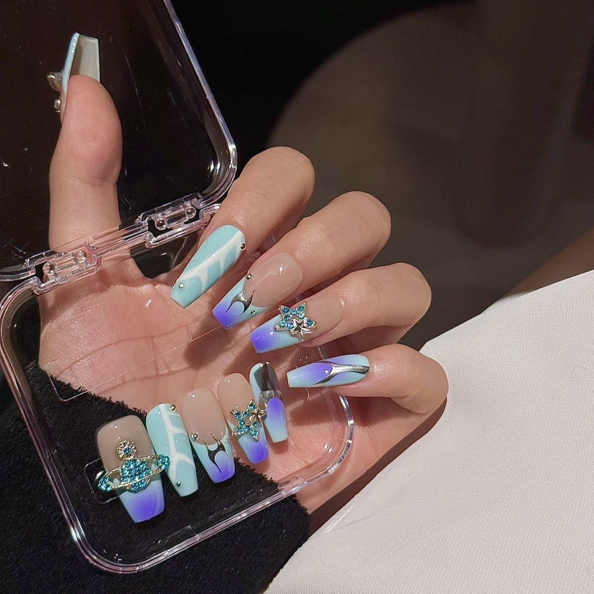 Galactic Glam Press-On Nails take you on a cosmic journey with their mesmerizing ombré of blue to lavender hues, paired with metallic accents and sparkling crystal charms. The planetary motifs and star-studded embellishments create a celestial vibe that’s perfect for the dreamer and stargazer at heart.