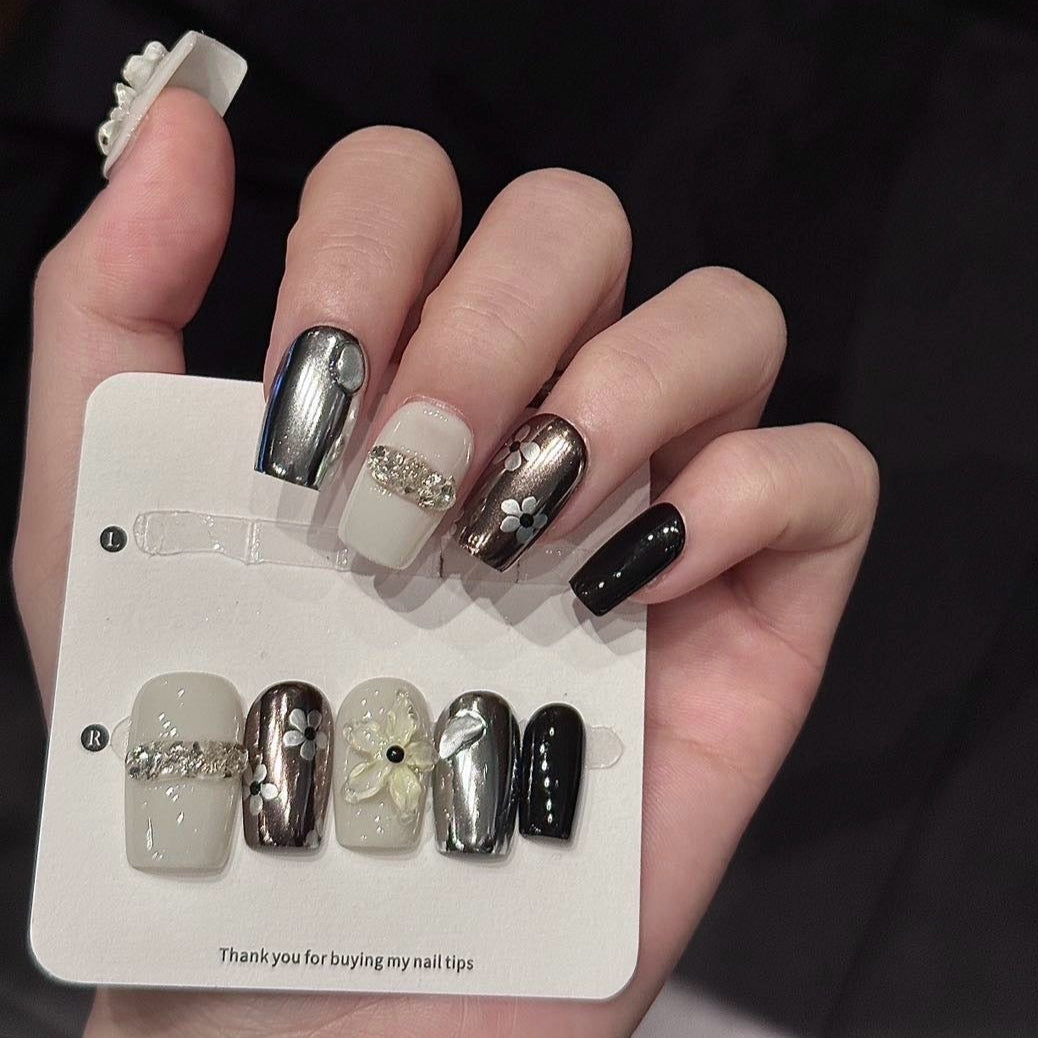 Embrace sophisticated elegance with Glam Noir Press-On Nails, a luxurious blend of glossy black, metallic silver, and creamy ivory adorned with 3D floral designs, sparkling gemstones, and bold metallic accents. This high-fashion set combines modern glamour with classic chic, featuring intricate floral motifs and dazzling crystal embellishments for a refined, statement look. With a glossy finish and structured square shape, Glam Noir exudes timeless sophistication and urban elegance.