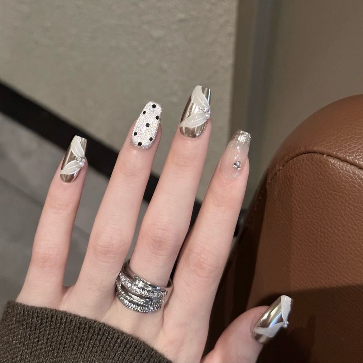 Glamour Noir Press-On Nails bring a sophisticated edge to your look with a chic palette of metallic silver, smoky grey, and bold black polka dots. Designed with elegant 3D ribbon accents and sparkling rhinestones, these nails offer a timeless yet modern flair perfect for evenings out or adding a touch of luxury to any outfit.
