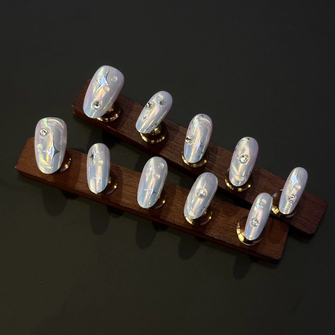 Holo Glow Press-On Nails bring futuristic brilliance to your fingertips with a mesmerizing holographic shimmer that catches light from every angle. These nails feature a glossy, iridescent finish with delicate star accents and crystal embellishments, perfect for adding a touch of magic to any look.