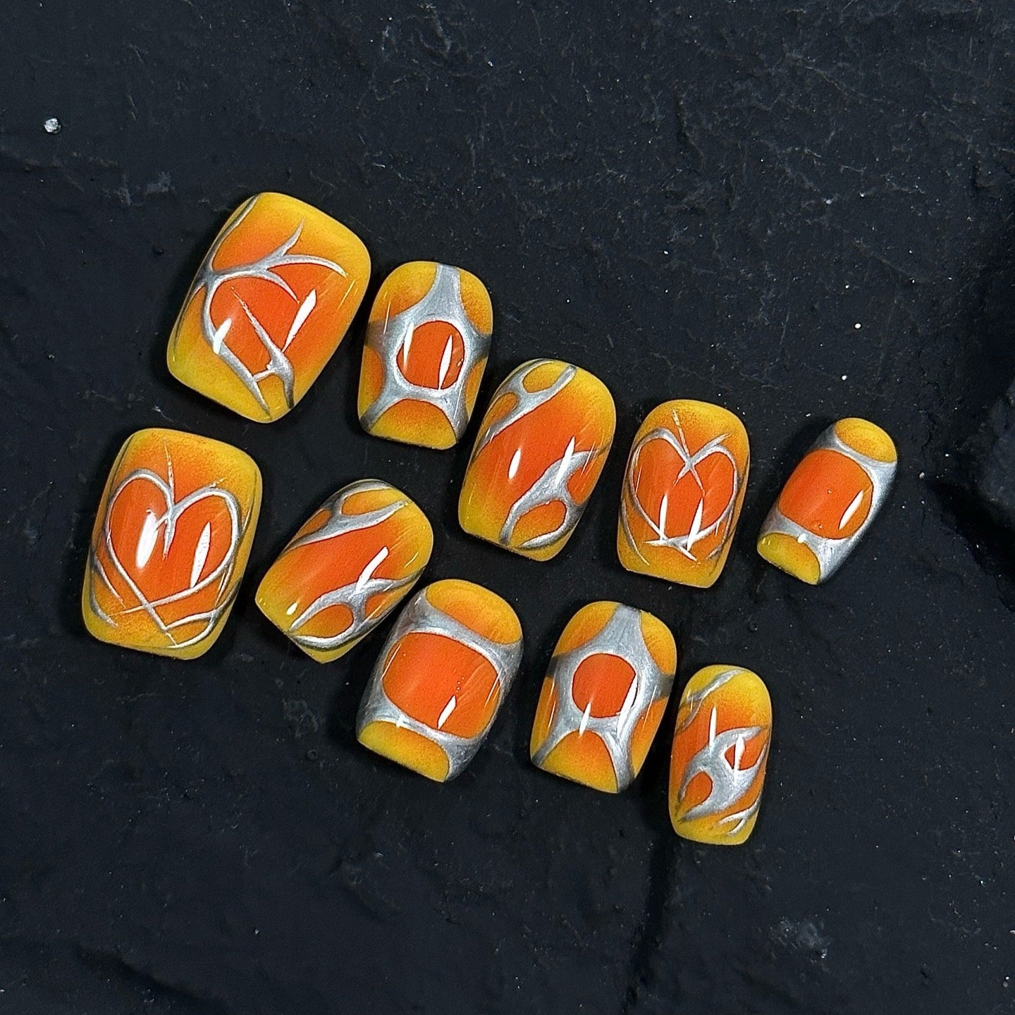 Inferno Swirl Press-On Nails ignite your style with a vibrant blend of fiery orange, golden yellow, and metallic silver. Designed with bold, abstract flame-like patterns, these nails bring an electrifying and dynamic look, perfect for those who love to make a statement.

