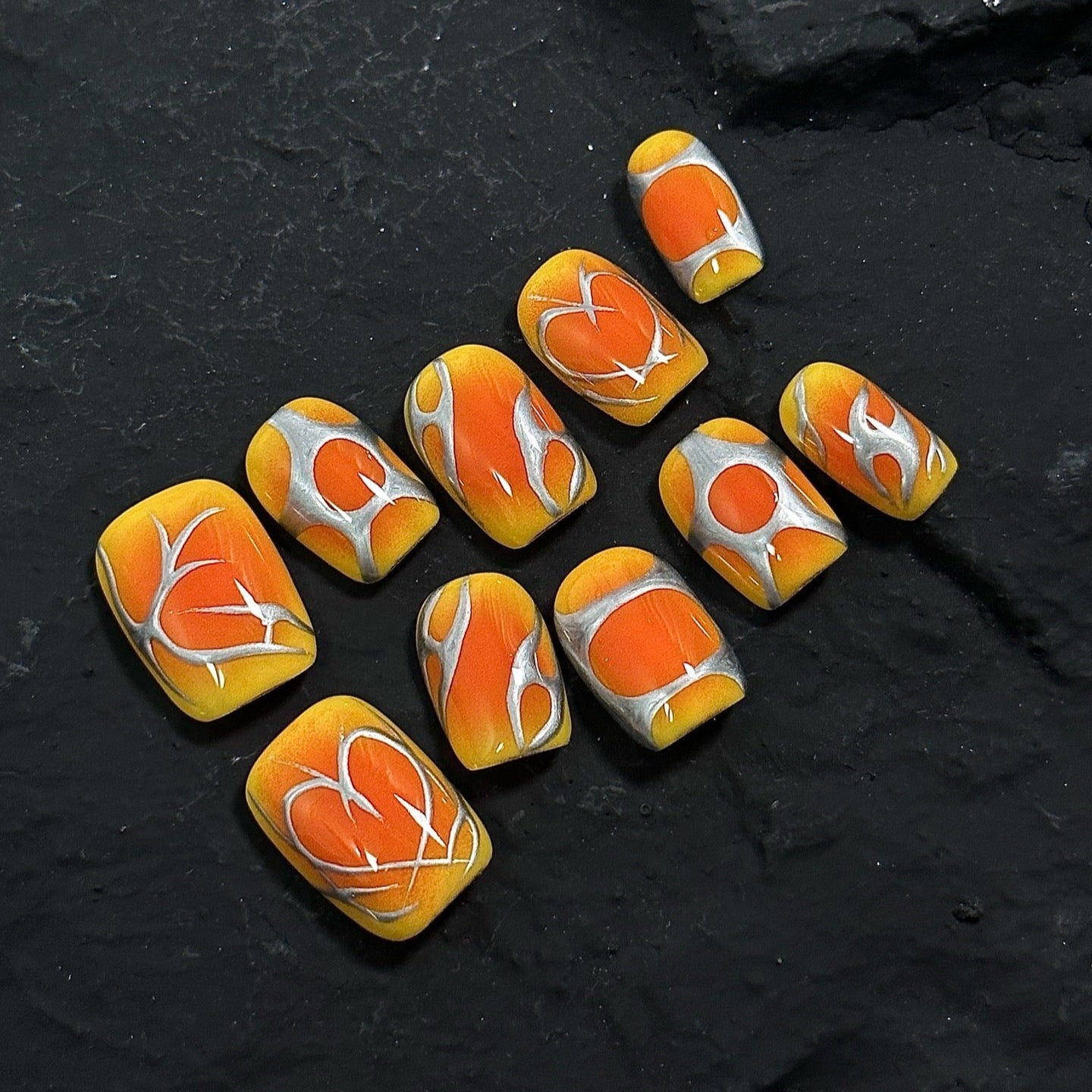 Inferno Swirl Press-On Nails ignite your style with a vibrant blend of fiery orange, golden yellow, and metallic silver. Designed with bold, abstract flame-like patterns, these nails bring an electrifying and dynamic look, perfect for those who love to make a statement.
