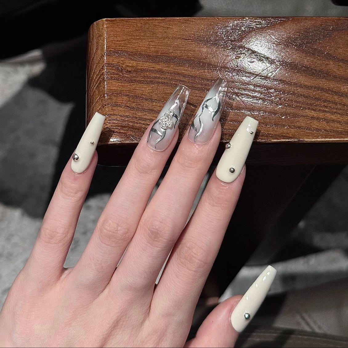 Step into a world of elegance and contrast with the Ivory Eclipse Press-On Nails, a sophisticated blend of creamy ivory and sleek metallic silver. This design combines modern minimalism with bold accents, making it perfect for those who love a refined yet striking aesthetic.