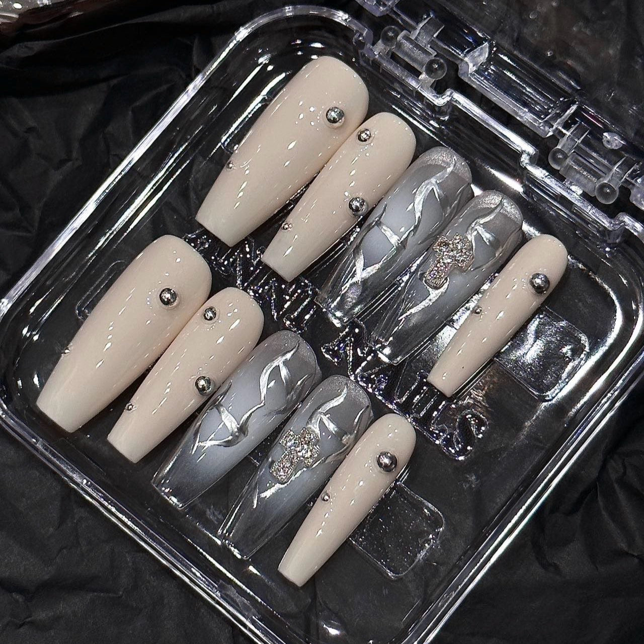 Step into a world of elegance and contrast with the Ivory Eclipse Press-On Nails, a sophisticated blend of creamy ivory and sleek metallic silver. This design combines modern minimalism with bold accents, making it perfect for those who love a refined yet striking aesthetic.