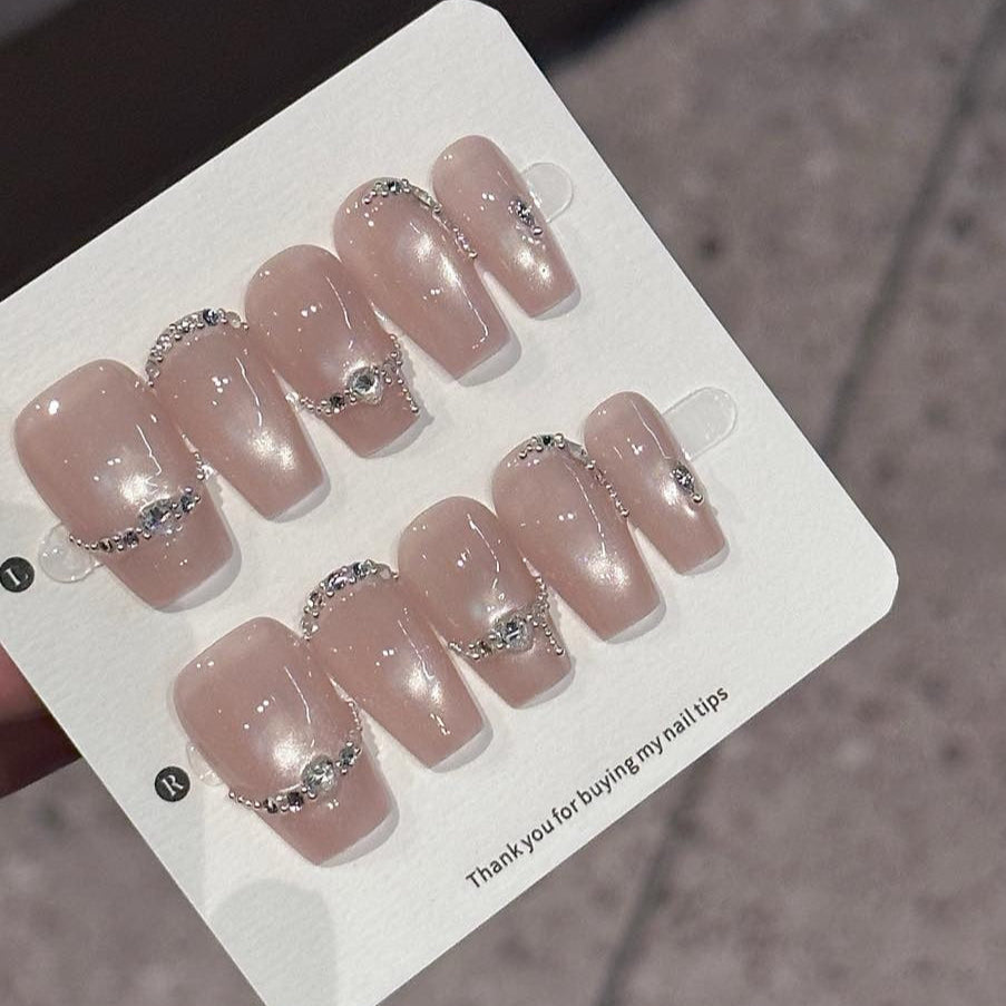 Embrace sophisticated elegance with Luxe Pearl Charm Press-On Nails, featuring a stunning blend of soft pearl pink and delicate silver chain accents adorned with sparkling gemstones. This luxurious set showcases a subtle shimmer that catches the light beautifully, creating an ethereal, radiant look. With a glossy finish and structured short square shape, Luxe Pearl Charm brings a touch of understated glamour and feminine grace to your fingertips.
