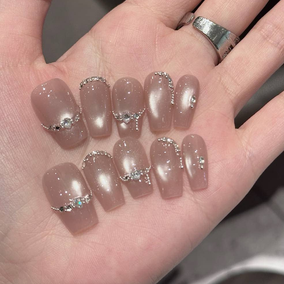 Embrace sophisticated elegance with Luxe Pearl Charm Press-On Nails, featuring a stunning blend of soft pearl pink and delicate silver chain accents adorned with sparkling gemstones. This luxurious set showcases a subtle shimmer that catches the light beautifully, creating an ethereal, radiant look. With a glossy finish and structured short square shape, Luxe Pearl Charm brings a touch of understated glamour and feminine grace to your fingertips.