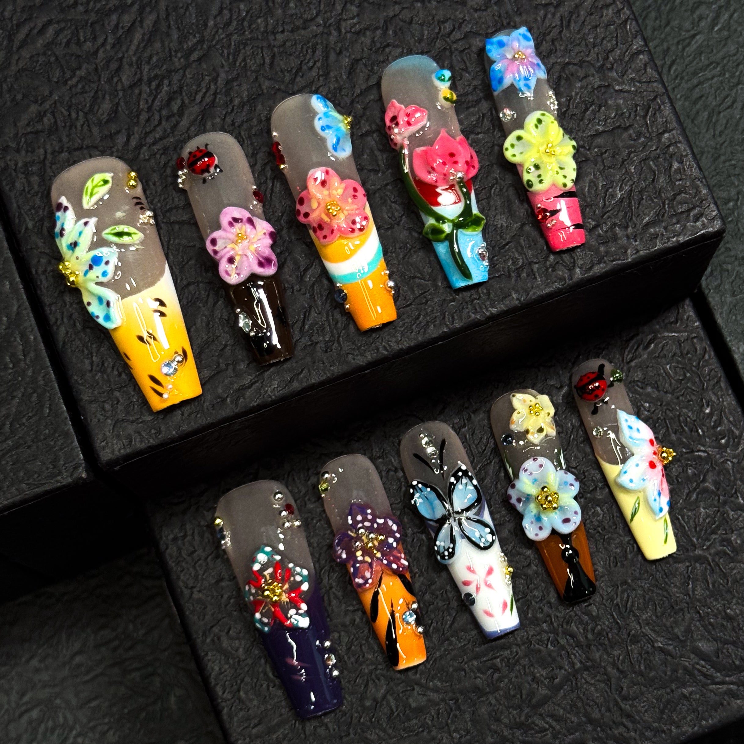 Vibrant Floral Palette: Hot pinks, teals, purples, yellows, and more—each nail like a wildflower in full bloom.
• 3D Garden Details: Sculpted butterflies, blossoms, and ladybugs bring a whimsical, storybook feel.
• Matte-to-Gloss Contrast: Smoky matte bases meet ultra-glossy, raised designs for textural drama.
• Nature-Inspired Artistry: Hand-painted stems, leaves, and wing details create a wearable garden on your fingertips.
• Long Coffin Shape: A sleek, squared-off silhouette perfect for showcasing