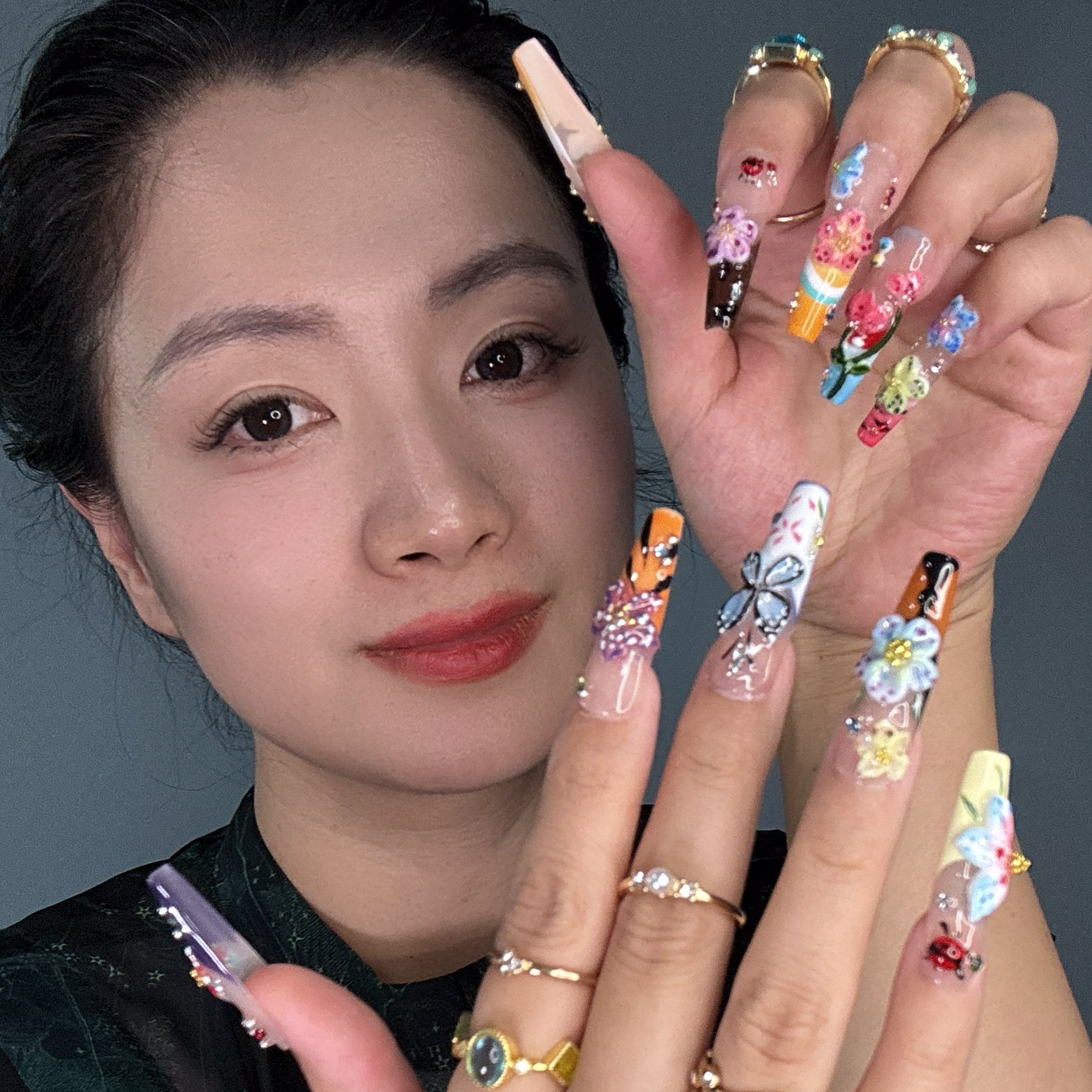 Vibrant Floral Palette: Hot pinks, teals, purples, yellows, and more—each nail like a wildflower in full bloom.
• 3D Garden Details: Sculpted butterflies, blossoms, and ladybugs bring a whimsical, storybook feel.
• Matte-to-Gloss Contrast: Smoky matte bases meet ultra-glossy, raised designs for textural drama.
• Nature-Inspired Artistry: Hand-painted stems, leaves, and wing details create a wearable garden on your fingertips.
• Long Coffin Shape: A sleek, squared-off silhouette perfect for showcasing