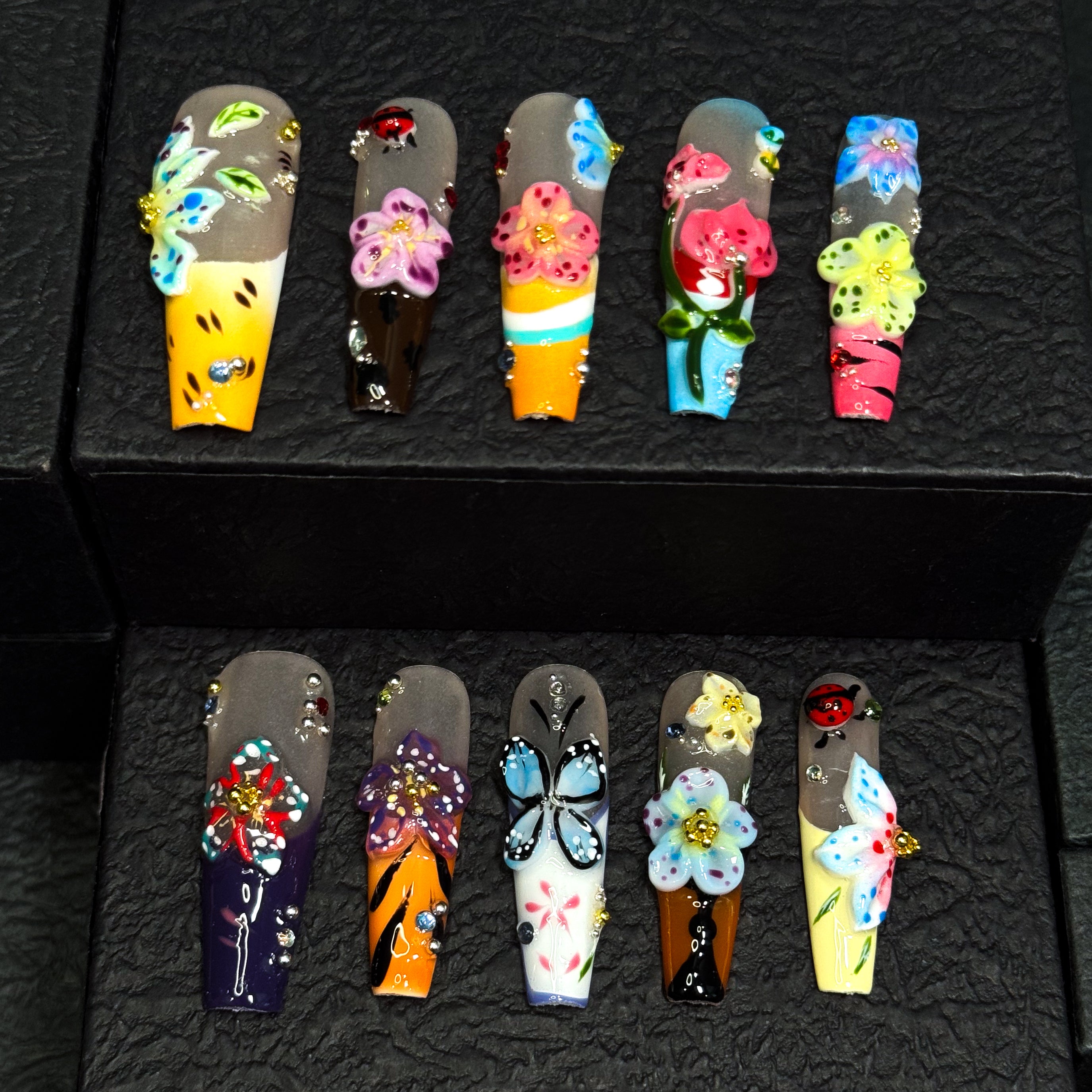 Vibrant Floral Palette: Hot pinks, teals, purples, yellows, and more—each nail like a wildflower in full bloom.
• 3D Garden Details: Sculpted butterflies, blossoms, and ladybugs bring a whimsical, storybook feel.
• Matte-to-Gloss Contrast: Smoky matte bases meet ultra-glossy, raised designs for textural drama.
• Nature-Inspired Artistry: Hand-painted stems, leaves, and wing details create a wearable garden on your fingertips.
• Long Coffin Shape: A sleek, squared-off silhouette perfect for showcasing