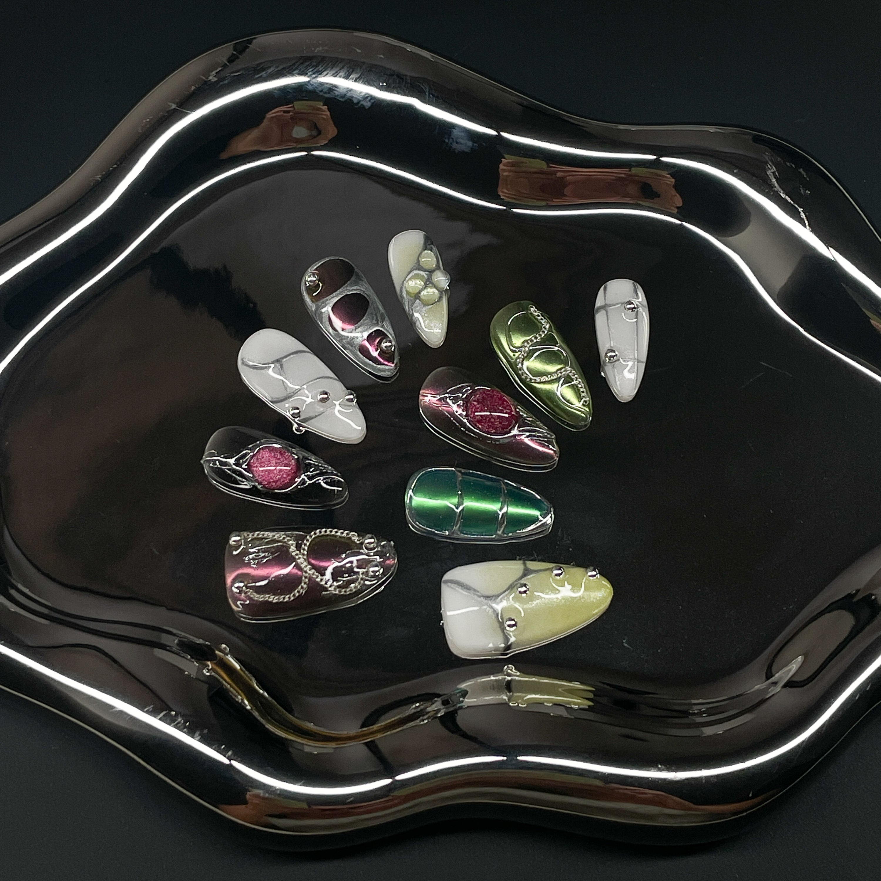 Sculpted Grid Pods: 3D gel bubbles in fuchsia, green, and pearl evoke high-fashion armor and insect shells.
• Fluid Chrome Details: Silver piping and reflective accents deliver an ultra-modern, cyber-organic vibe.
• Luxe Neutrals & Jewel Tones: Glossy whites, soft olives, and deep magentas play with electric contrast.
• Mixed Texture Finish: Smooth marble swirls, pearlescent gradients, and sculpted dimensional forms.
• Almond Shape: A sleek, wearable silhouette that keeps the avant-garde design effortlessly