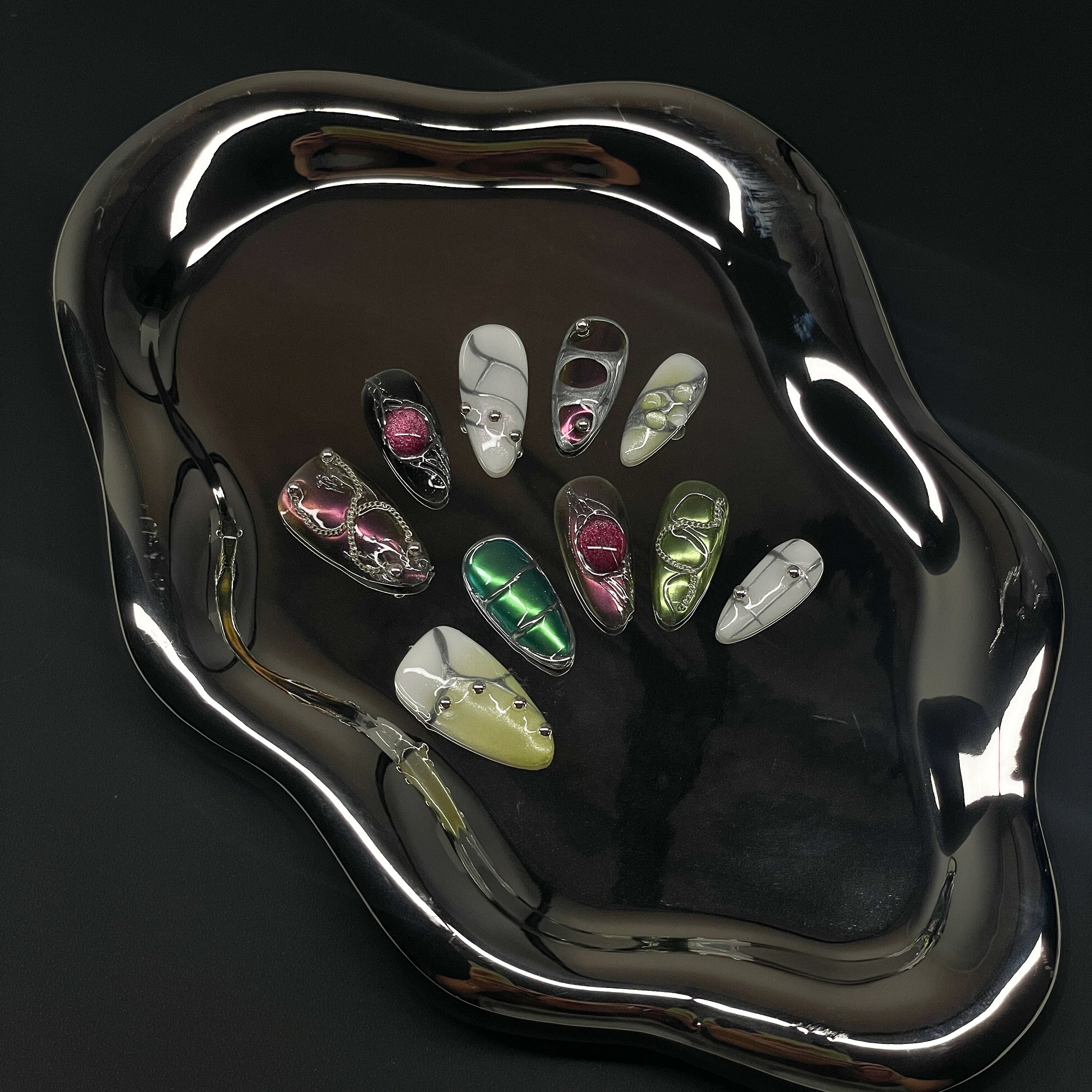 Sculpted Grid Pods: 3D gel bubbles in fuchsia, green, and pearl evoke high-fashion armor and insect shells.
• Fluid Chrome Details: Silver piping and reflective accents deliver an ultra-modern, cyber-organic vibe.
• Luxe Neutrals & Jewel Tones: Glossy whites, soft olives, and deep magentas play with electric contrast.
• Mixed Texture Finish: Smooth marble swirls, pearlescent gradients, and sculpted dimensional forms.
• Almond Shape: A sleek, wearable silhouette that keeps the avant-garde design effortlessly