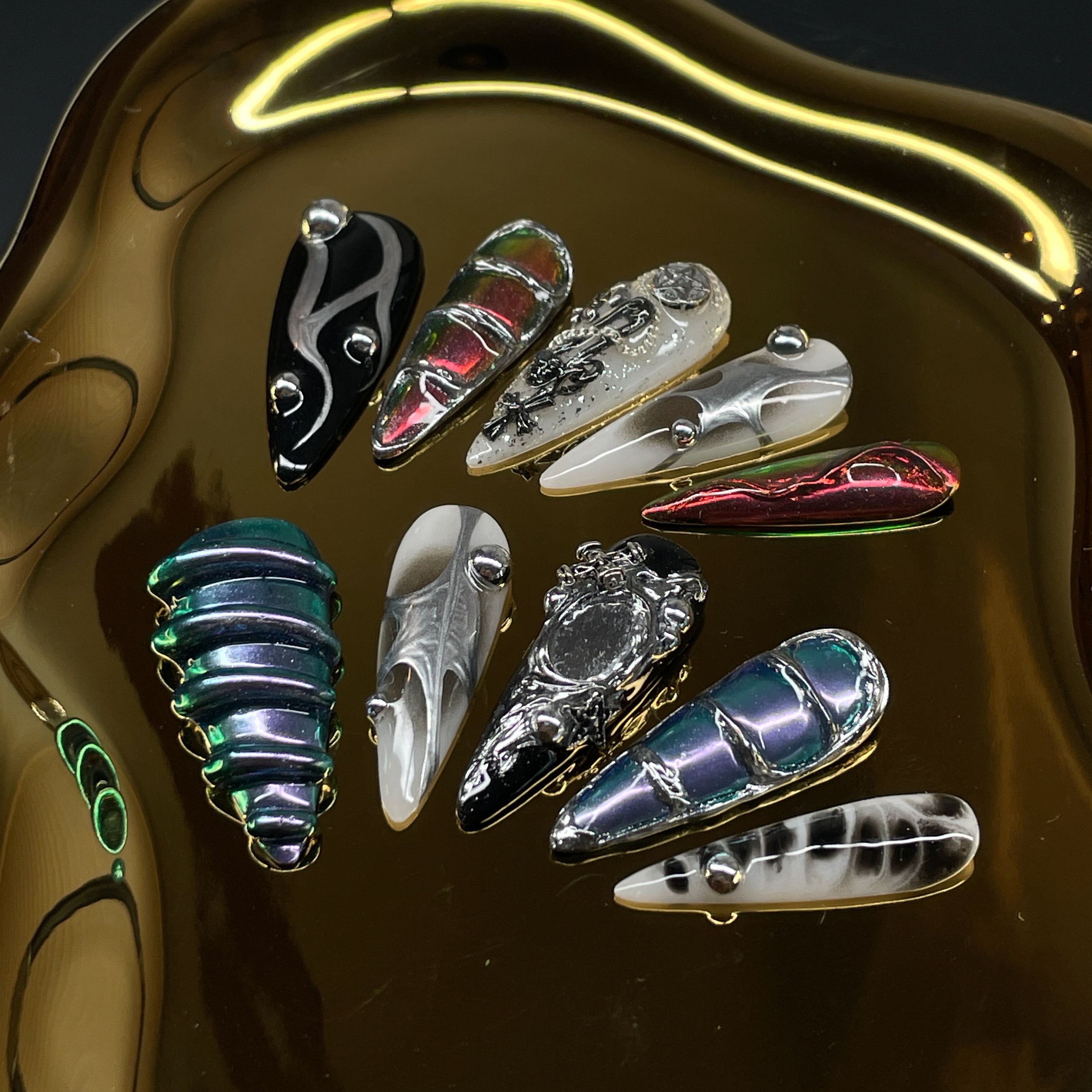 Futuristic Color Clash: Electric blue, blood red, and bone white swirl against chrome black for an ultra-modern contrast.
• 3D Sculptural Texture: Raised silver spheres and layered gel details create depth and motion.
• Glitch Art Motifs: Bold linework, chaotic patterns, and fragmented symmetry evoke digital distortion.
• Metallic Mirror Finish: Sleek chrome effects reflect light like machine parts in motion.
• Almond Shape: A perfect fusion of edgy and wearable, ideal for cyber sirens and digital rebels al