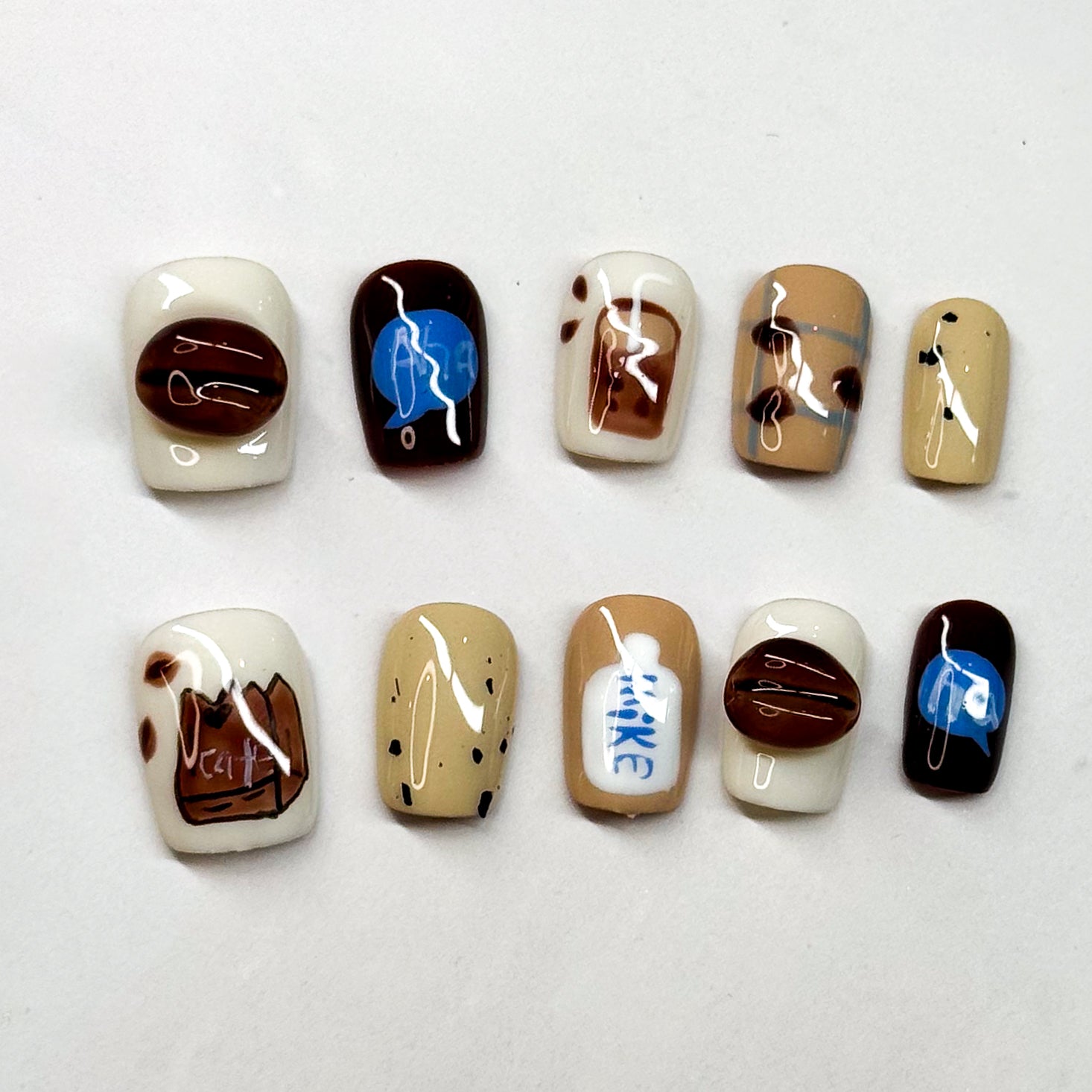 Café Inspired: Includes coffee bean accents, milk carton details, and mocha swirls.
• Cozy Colors: Warm neutrals of cream, caramel, and espresso with pops of blue.
• Short Square Shape: Practical and stylish, perfect for everyday wear.
• Coffee Lover’s Dream: A must-have set for baristas, caffeine fans, or anyone obsessed with café vibes.
• Reusable & Durable: Handmade with premium gel for long-lasting wear.