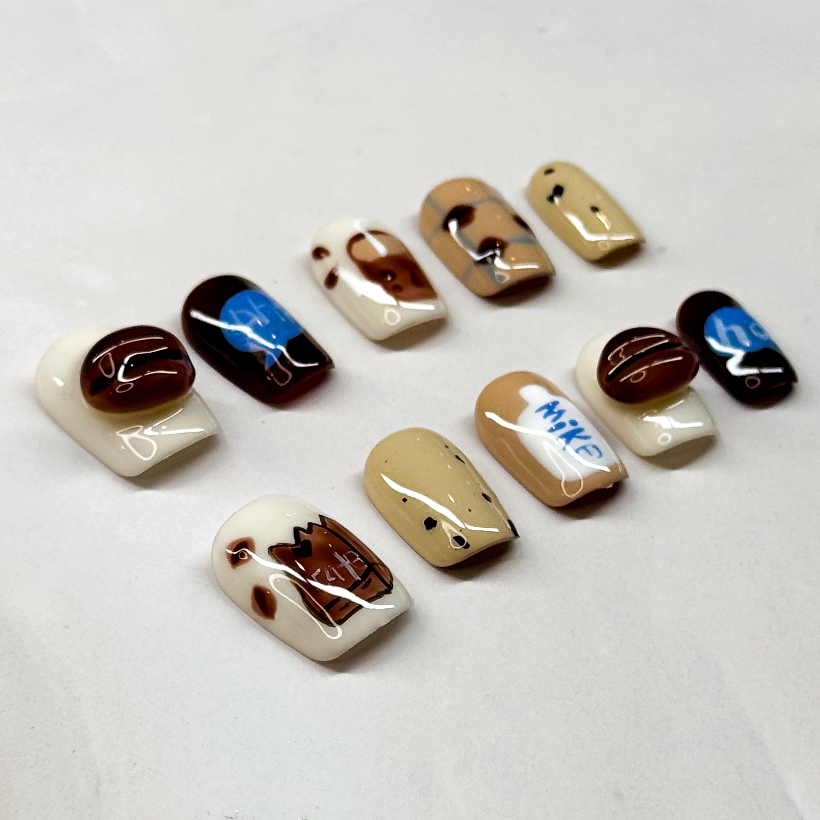Café Inspired: Includes coffee bean accents, milk carton details, and mocha swirls.
• Cozy Colors: Warm neutrals of cream, caramel, and espresso with pops of blue.
• Short Square Shape: Practical and stylish, perfect for everyday wear.
• Coffee Lover’s Dream: A must-have set for baristas, caffeine fans, or anyone obsessed with café vibes.
• Reusable & Durable: Handmade with premium gel for long-lasting wear.
