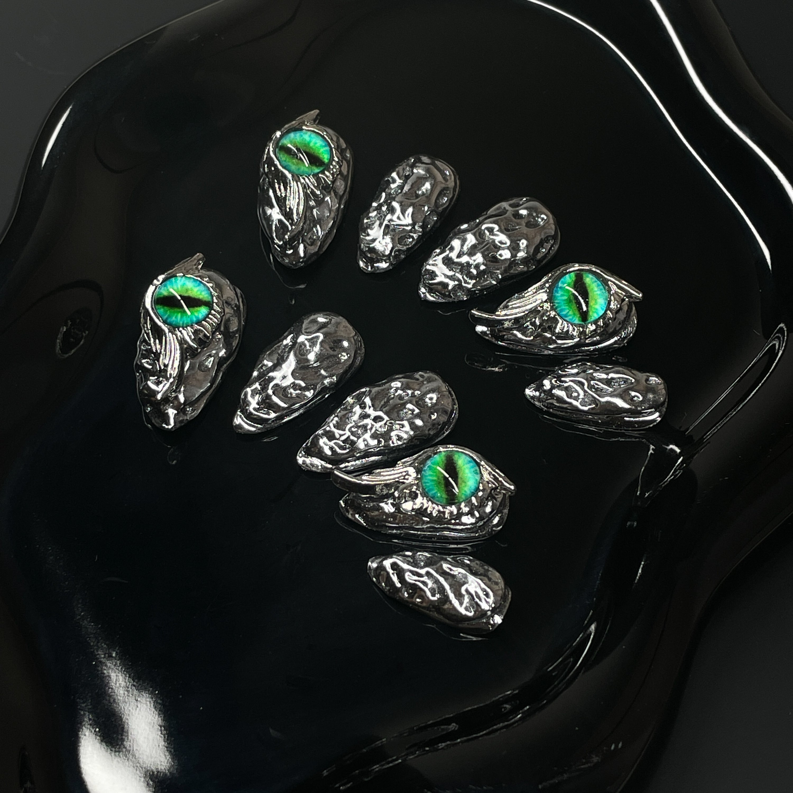 Chrome Scale Texture: Irregular molten metal surface mimics dragon hide with a futuristic edge.
• Striking Green Eyes: Hand-placed dragon eye orbs add hypnotic intensity and a fierce focal point.
• 3D Sculpted Armor: Metallic claws and raised textures evoke a battle-ready fantasy aesthetic.
• High-Shine Finish: Ultra-reflective silver coating for a sleek, high-impact look.
• Almond Shape: Balanced and bold—perfect for commanding attention while staying elegant.