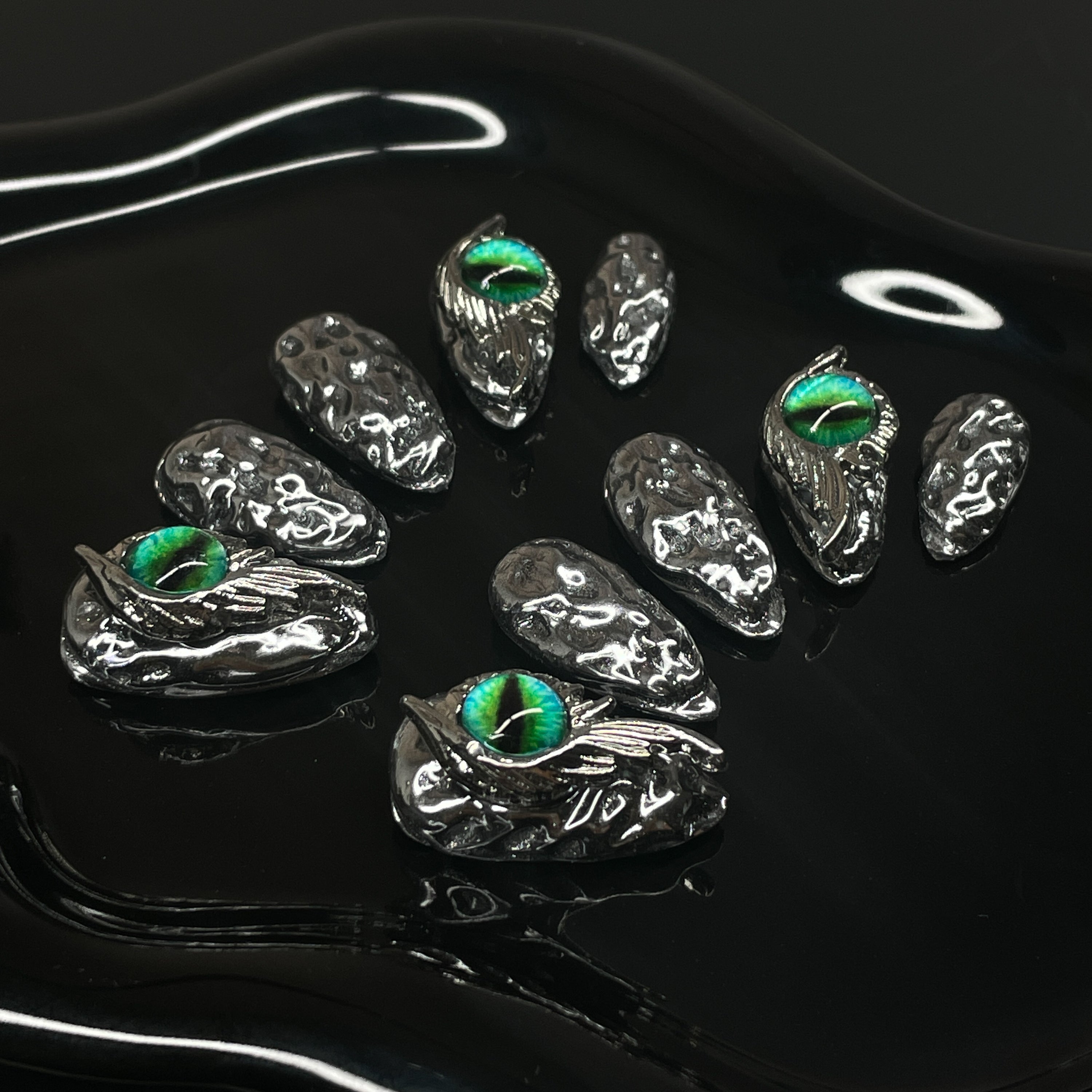 Chrome Scale Texture: Irregular molten metal surface mimics dragon hide with a futuristic edge.
• Striking Green Eyes: Hand-placed dragon eye orbs add hypnotic intensity and a fierce focal point.
• 3D Sculpted Armor: Metallic claws and raised textures evoke a battle-ready fantasy aesthetic.
• High-Shine Finish: Ultra-reflective silver coating for a sleek, high-impact look.
• Almond Shape: Balanced and bold—perfect for commanding attention while staying elegant.