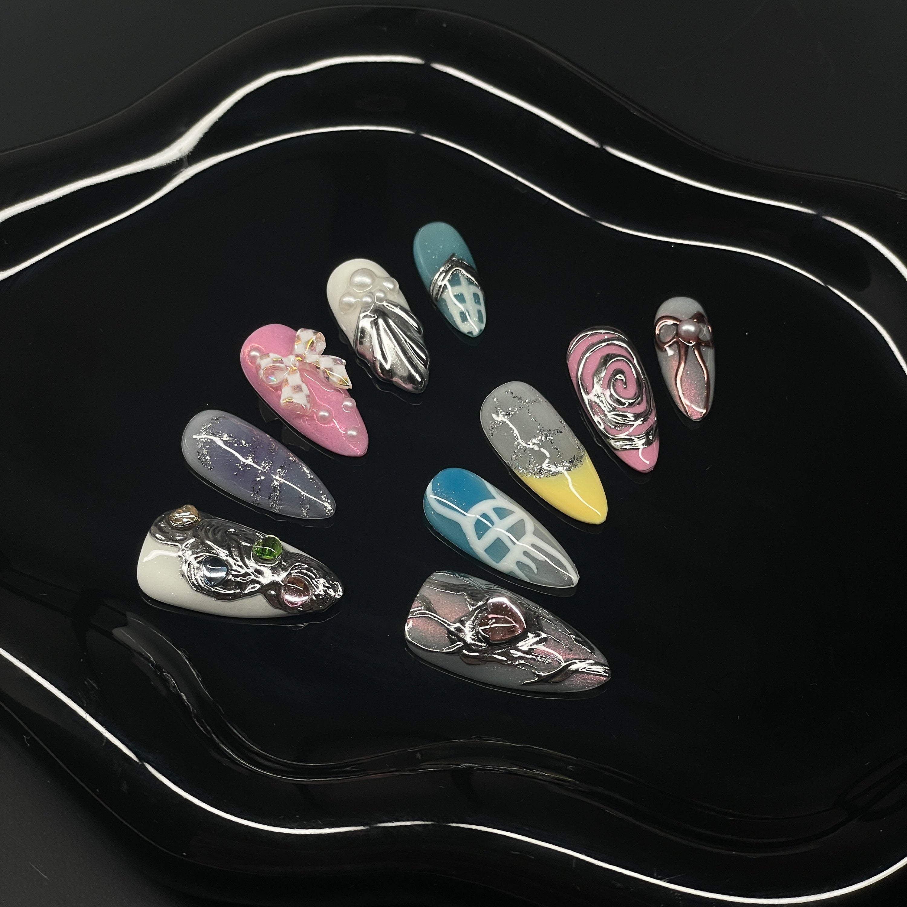 Pastel Playground: Baby pinks, sunny yellows, sky blues, and creamy whites form a sweet but striking palette.
• Mixed Media Magic: From hand-sculpted chrome faces to embedded pearls and glitter trails, this set celebrates playful contrasts.
• Futuristic Motifs: Cyber-bows, digital mesh lines, and chrome roses feel like soft tech dreams rendered IRL.
• 3D Textures & Layers: Embellished with hearts, ribbons, and bubble forms for rich, tactile dimension.
• Almond Shape: A soft, elegant silhouette that balances