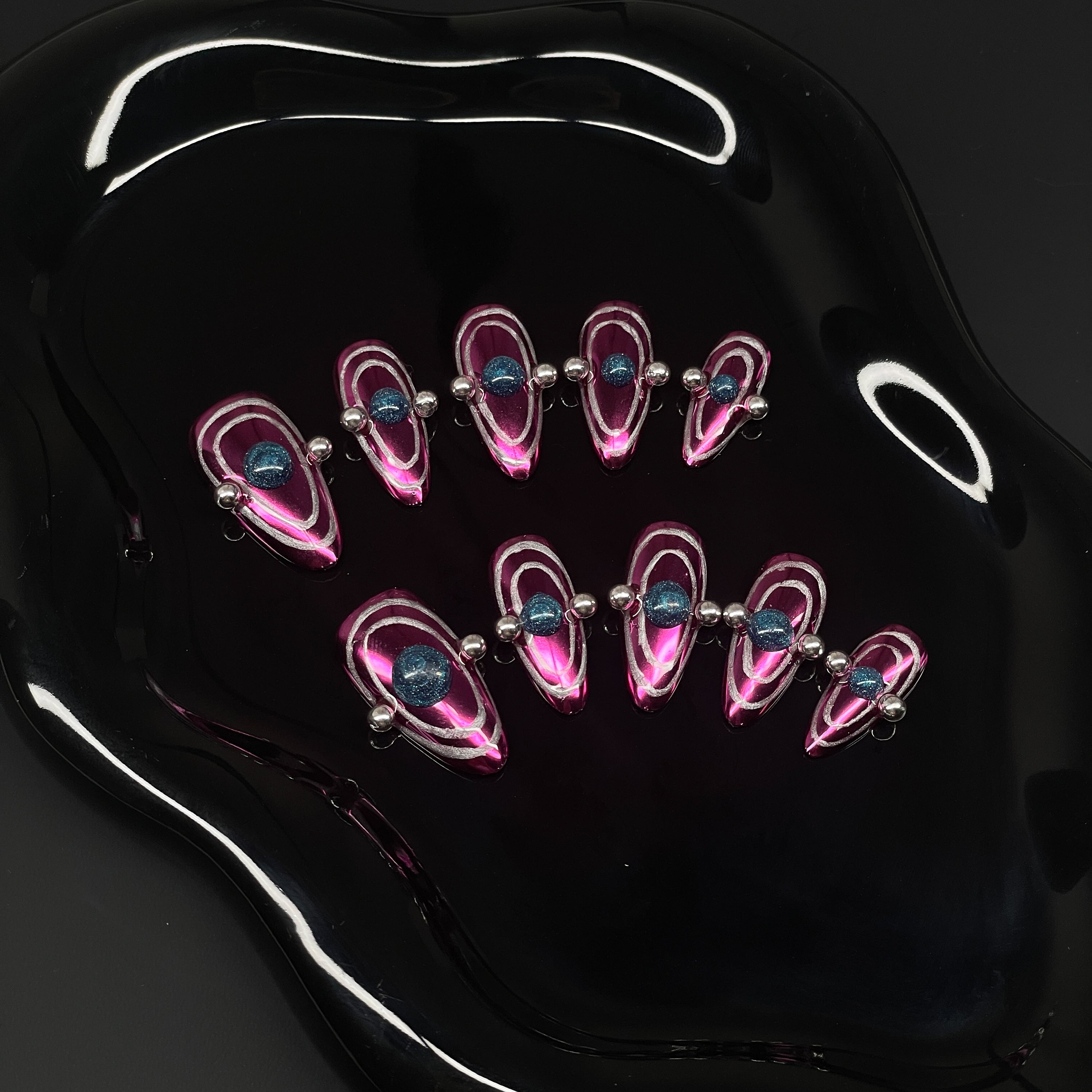 Chrome Pink Power: Vibrant metallic fuchsia base that shines like space metal under starlight.
• Orbital Illusion: Layered rings and 3D gel spheres give the look of planetary motion and galactic pull.
• Metallic Silver Beads: Accented with reflective chrome dots for a hyper-modern, kinetic feel.
• Dimensional Energy: Bold shapes and colors create a striking, space-age optical illusion.
• Almond Shape: Sleek, tapered tips keep the interstellar design elegant and wearable.