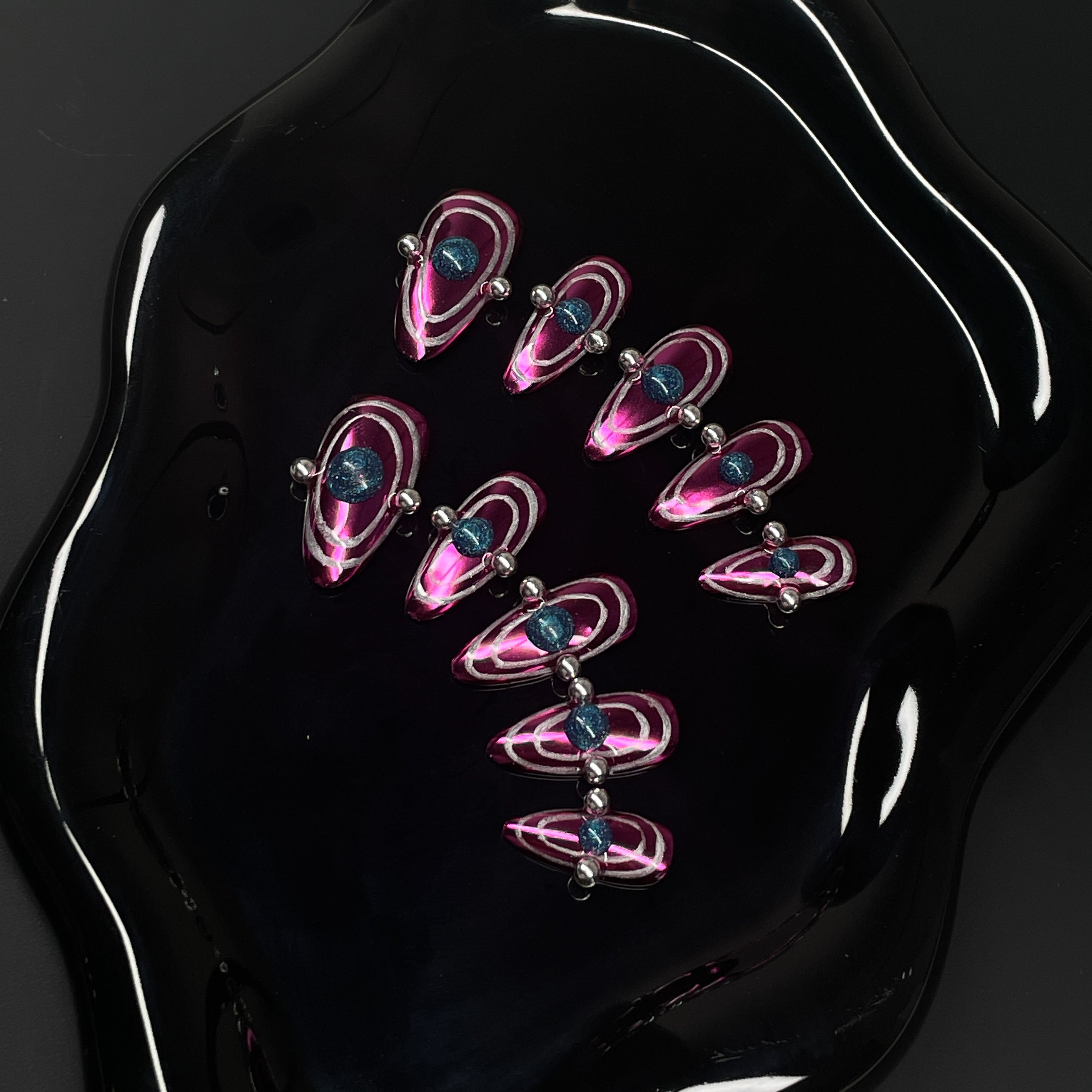 Chrome Pink Power: Vibrant metallic fuchsia base that shines like space metal under starlight.
• Orbital Illusion: Layered rings and 3D gel spheres give the look of planetary motion and galactic pull.
• Metallic Silver Beads: Accented with reflective chrome dots for a hyper-modern, kinetic feel.
• Dimensional Energy: Bold shapes and colors create a striking, space-age optical illusion.
• Almond Shape: Sleek, tapered tips keep the interstellar design elegant and wearable.