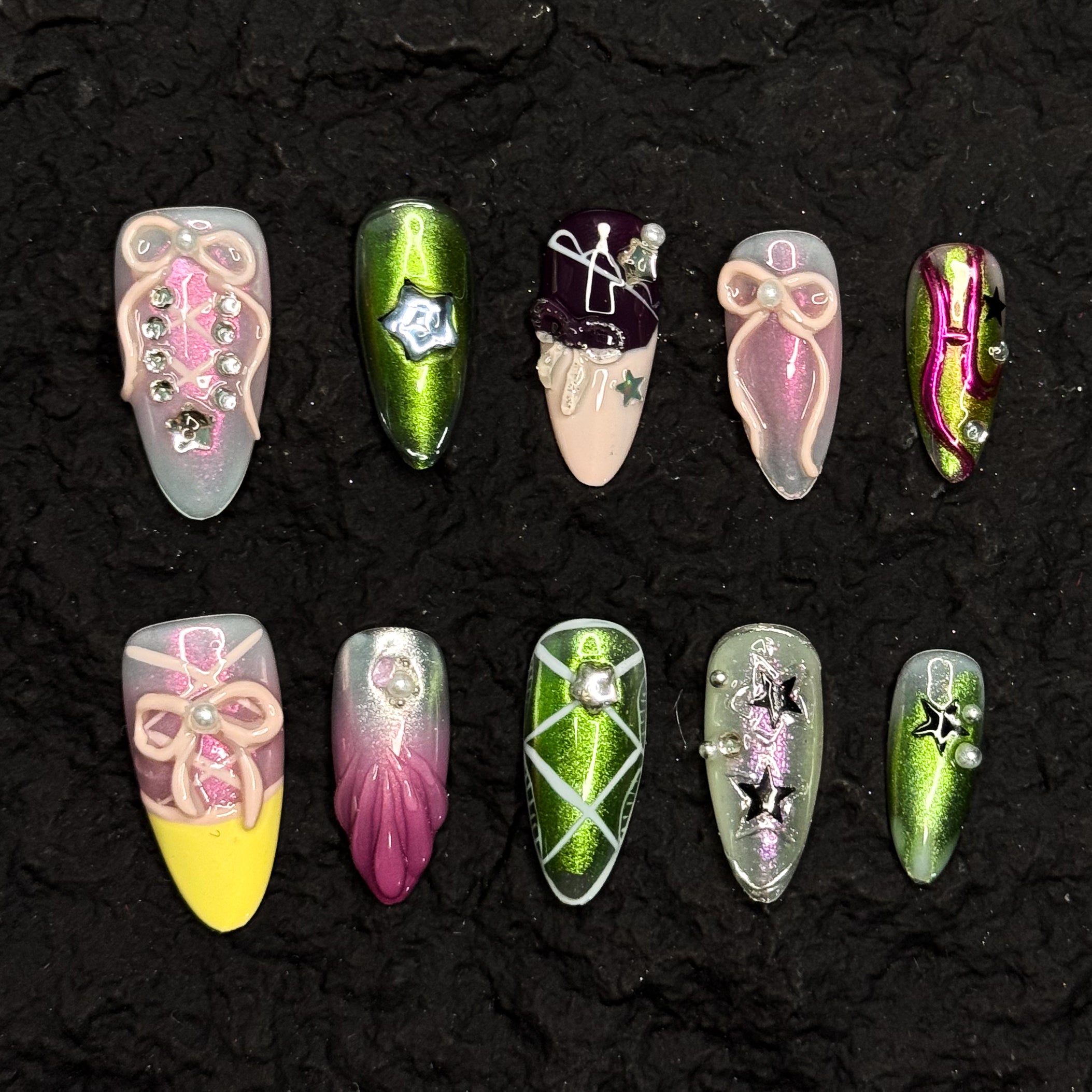 Futuristic Chrome: Electric green metallic finishes with shifting reflections for a space-age vibe.
• Gradient Candy Colors: Soft pinks, bold yellows, and glossy lilacs in dreamy ombrés.
• 3D Sculptural Accents: Bows, pearls, star charms, and layered ribbons add dramatic dimension.
• Celestial Details: Silver stars, gems, and metallic striping evoke constellations and galactic energy.
• Almond Shape: Perfectly tapered to balance the maximalist design with wearable elegance.