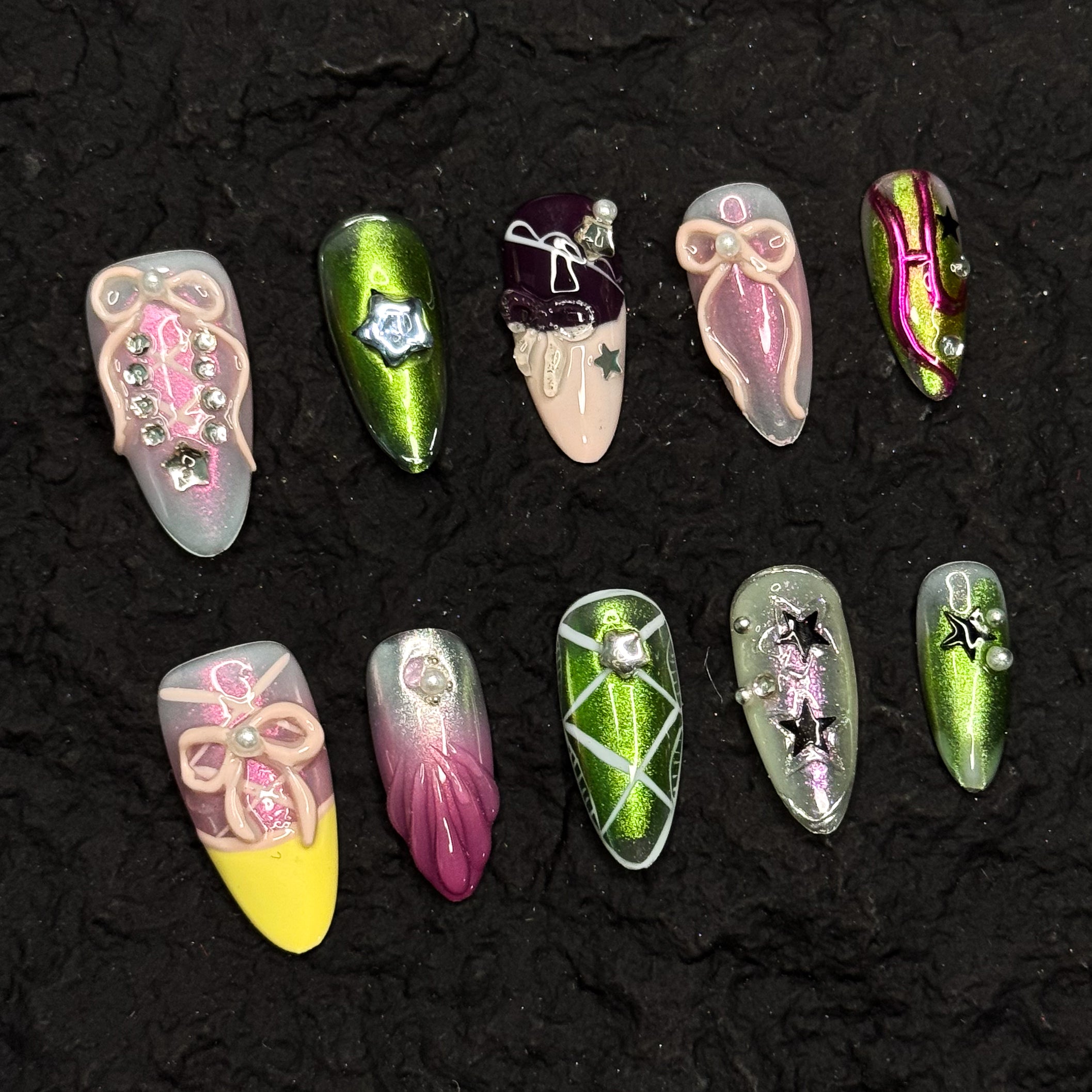 Futuristic Chrome: Electric green metallic finishes with shifting reflections for a space-age vibe.
• Gradient Candy Colors: Soft pinks, bold yellows, and glossy lilacs in dreamy ombrés.
• 3D Sculptural Accents: Bows, pearls, star charms, and layered ribbons add dramatic dimension.
• Celestial Details: Silver stars, gems, and metallic striping evoke constellations and galactic energy.
• Almond Shape: Perfectly tapered to balance the maximalist design with wearable elegance.