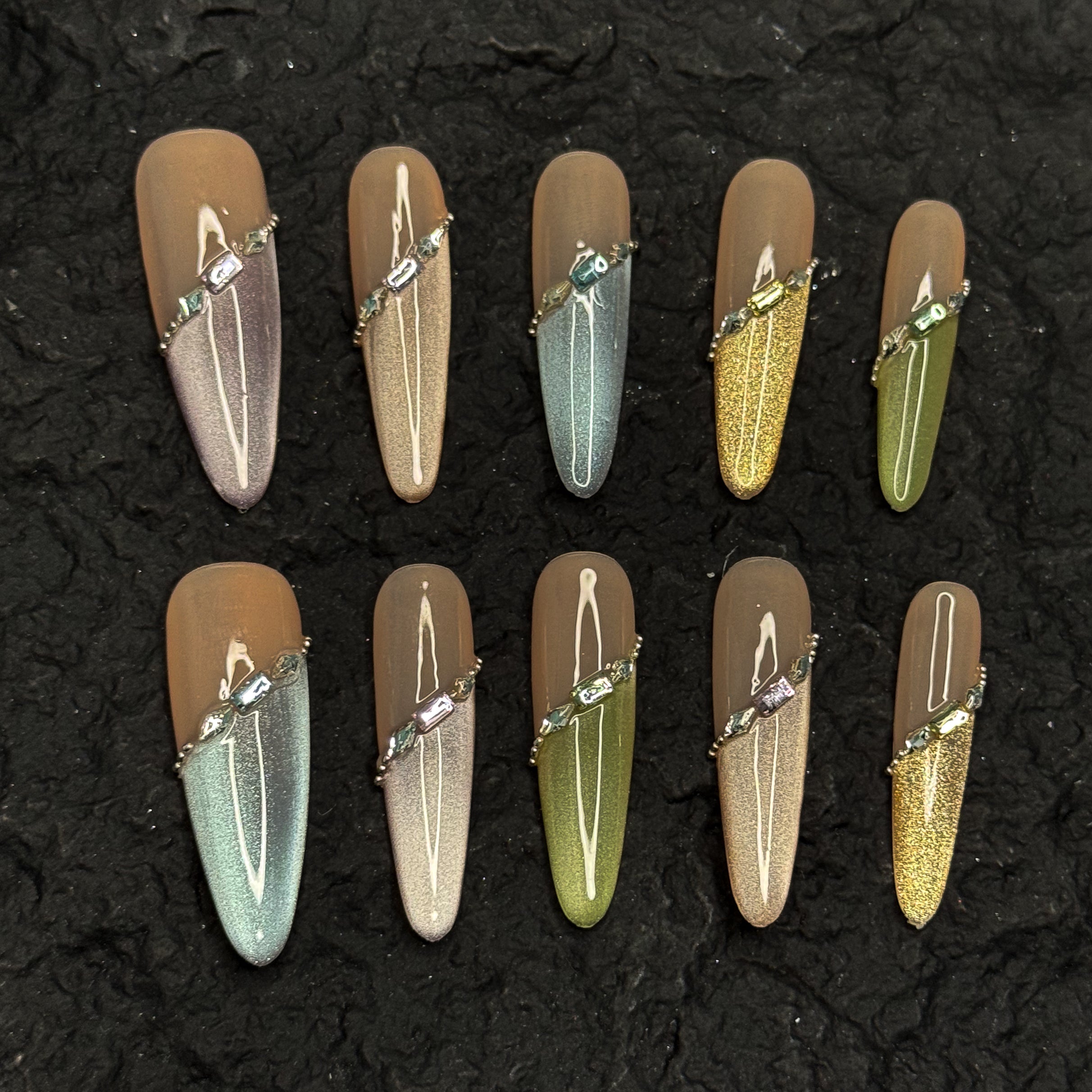 Nude Foundation: Neutral, semi-sheer base tones that flatter every skin tone while keeping things sophisticated.
• Shimmer Gradient: Subtle ombré sparkle in pastel greens, silvers, golds, and blues for a dreamy veil effect.
• Jewel Strap Detail: Diagonal crystal-embellished line wraps the nail like fine jewelry, adding high-end polish.
• Metallic Accents: Tiny gold beads frame the design, balancing shine with softness.
• Long Coffin Shape: Elegant length and squared-off tip ideal for both special events and