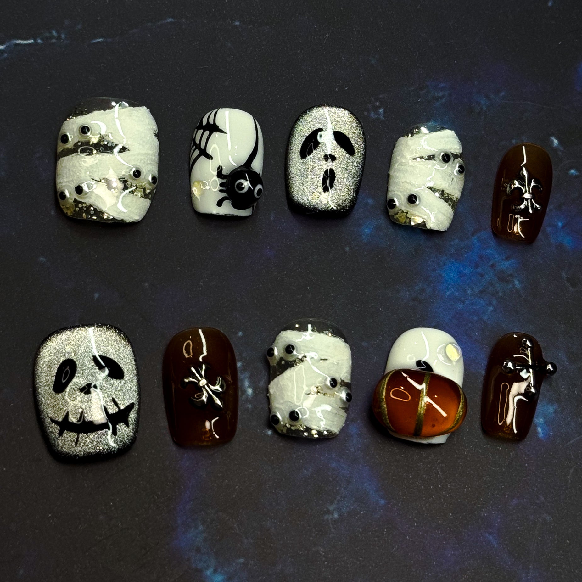 Spooky, playful, and full of Halloween charm — Haunted Night brings the spirit of October to your fingertips with a mix of mummy wraps, ghostly faces, and glowing pumpkins.
Key Features:
• Spooky Cute: Adorable mummy, ghost, and pumpkin designs hand-sculpted in 3D gel.
• Seasonal Shades: Classic Halloween tones of black, white, and orange with a glossy finish.
• Short Square Shape: Comfortable to wear daily while keeping the festive vibe.
• Party Ready: Perfect for trick-or-treating, costume parties, or jus