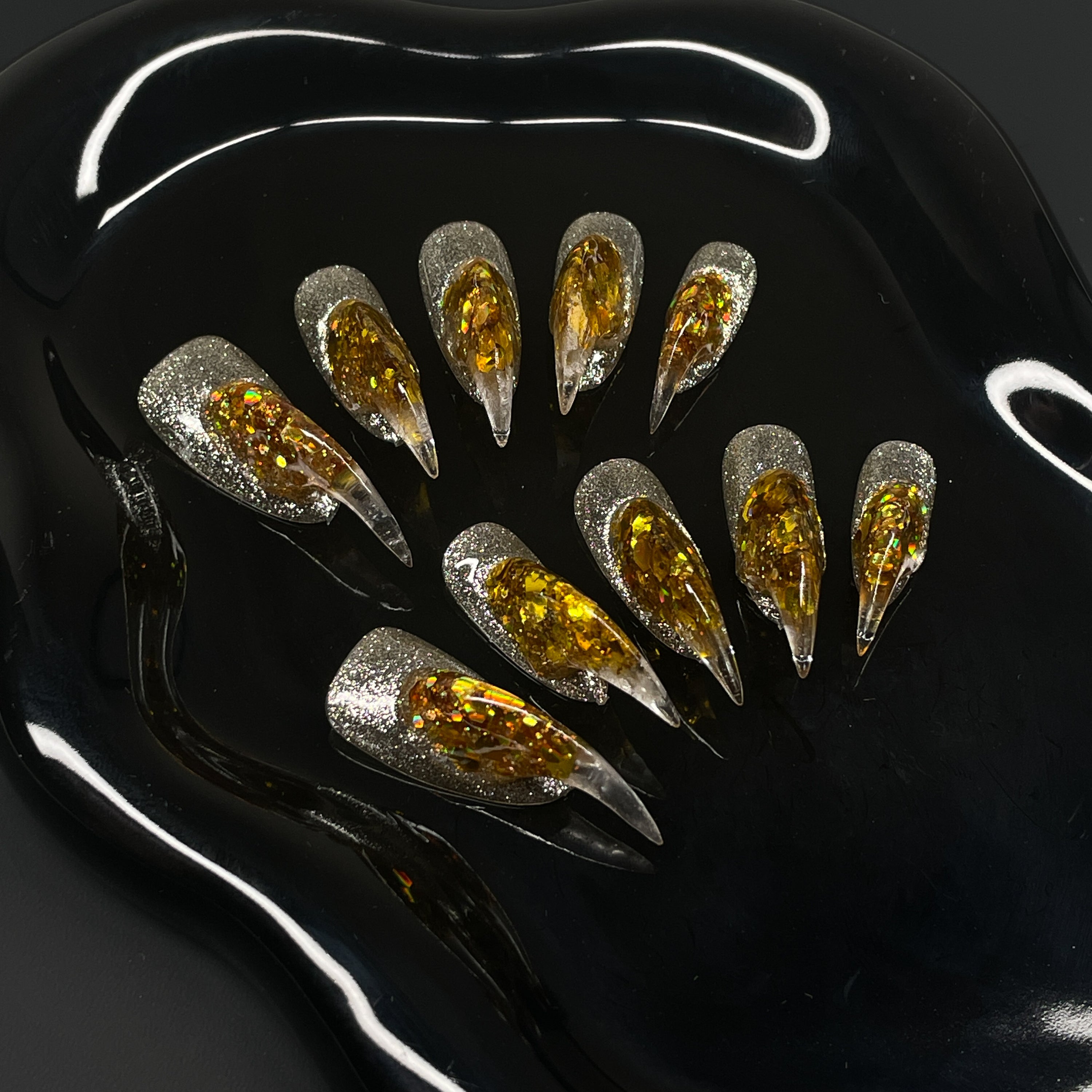  Holographic Gold Core: Encased flake foil burns bright inside a clear, sculpted gel spike.
• Silver Glitter Base: A sparkling foundation adds icy contrast to the molten glow.
• Fierce 3D Sculpting: Each nail rises into a pointed, claw-like peak for maximum visual impact.
• Light-Catching Brilliance: Multidimensional shine that shifts with every move.
• Claw Shape: Aggressively sculpted tips for a fierce, futuristic finish that bites back.