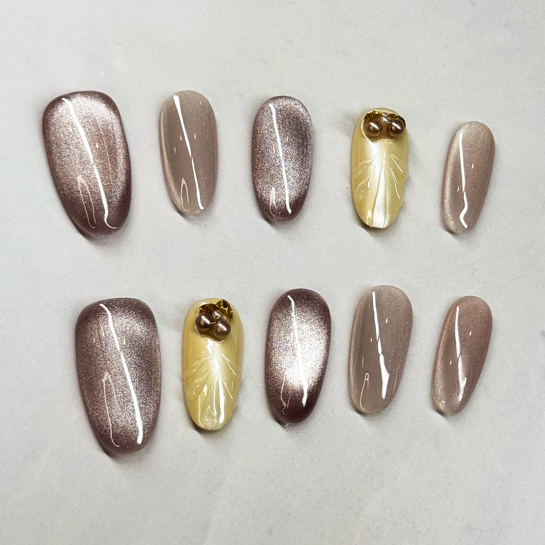 Chic Shades: A mix of metallic mocha and soft champagne nude.

• Subtle Glam: Shimmer effect that catches the light beautifully without being too loud.

• 3D Pearl Accents: Small pearl and gem details add a touch of understated luxury.

• Medium Oval Shape: Easy to wear every day while keeping the refined vibe.

• Versatile Style: Perfect for work, events, or an elegant everyday look.