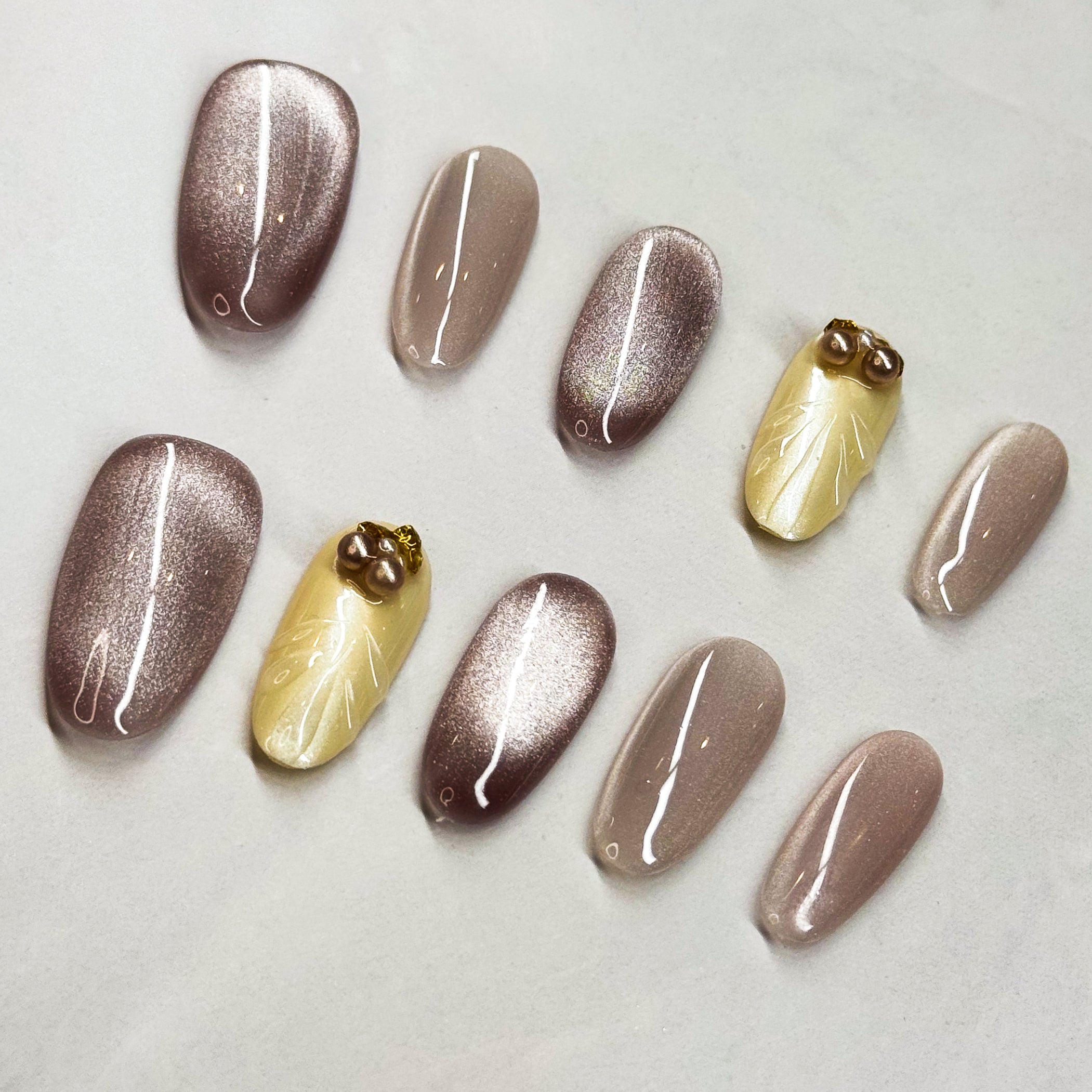 Chic Shades: A mix of metallic mocha and soft champagne nude.

• Subtle Glam: Shimmer effect that catches the light beautifully without being too loud.

• 3D Pearl Accents: Small pearl and gem details add a touch of understated luxury.

• Medium Oval Shape: Easy to wear every day while keeping the refined vibe.

• Versatile Style: Perfect for work, events, or an elegant everyday look.