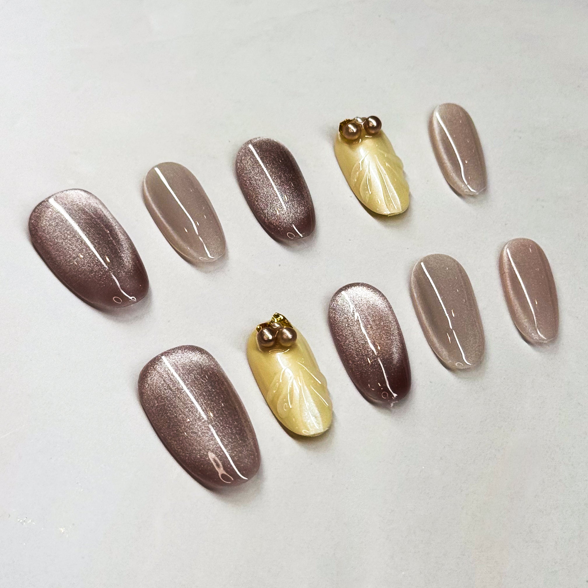 Chic Shades: A mix of metallic mocha and soft champagne nude.

• Subtle Glam: Shimmer effect that catches the light beautifully without being too loud.

• 3D Pearl Accents: Small pearl and gem details add a touch of understated luxury.

• Medium Oval Shape: Easy to wear every day while keeping the refined vibe.

• Versatile Style: Perfect for work, events, or an elegant everyday look.