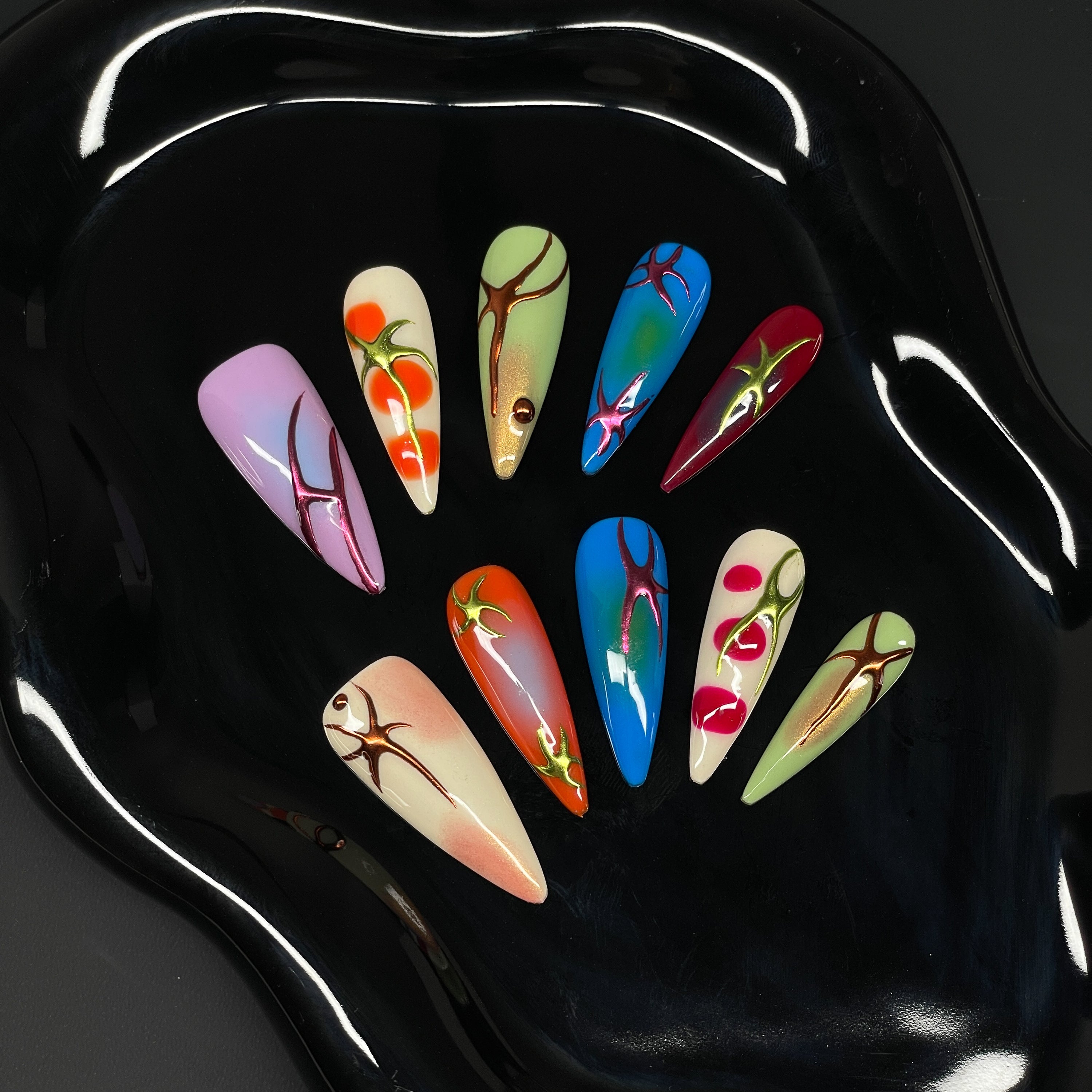 High-Voltage Color: Bright gradients of cherry red, tangerine, electric blue, and acid green pulse across each nail.
• 3D Root-Like Designs: Glossy sculpted accents twist and sprawl like growing vines or energetic flame streaks.
• Gloss & Glow Finish: Smooth, radiant surfaces with just the right amount of sheen to reflect your wild side.
• Unique Per Nail: Each piece is a one-of-a-kind statement—no two roots grow the same way.
• Long Stiletto Shape: Dramatic, elongated points for a high-impact silhouette th