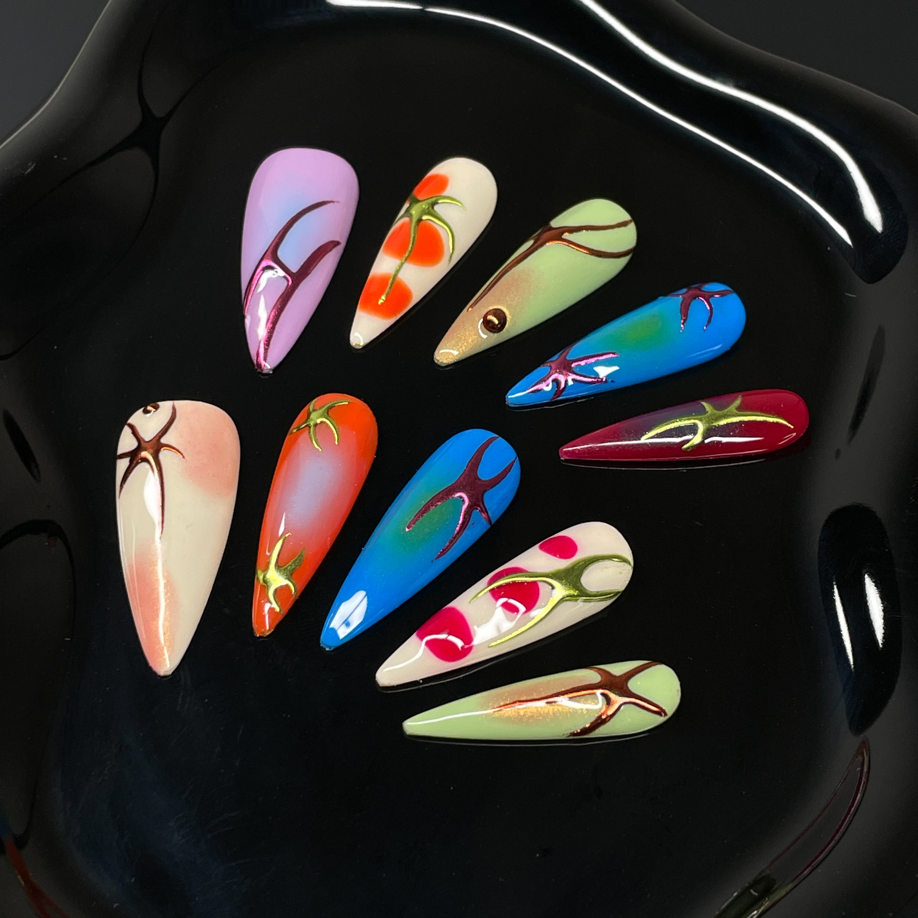 High-Voltage Color: Bright gradients of cherry red, tangerine, electric blue, and acid green pulse across each nail.
• 3D Root-Like Designs: Glossy sculpted accents twist and sprawl like growing vines or energetic flame streaks.
• Gloss & Glow Finish: Smooth, radiant surfaces with just the right amount of sheen to reflect your wild side.
• Unique Per Nail: Each piece is a one-of-a-kind statement—no two roots grow the same way.
• Long Stiletto Shape: Dramatic, elongated points for a high-impact silhouette th