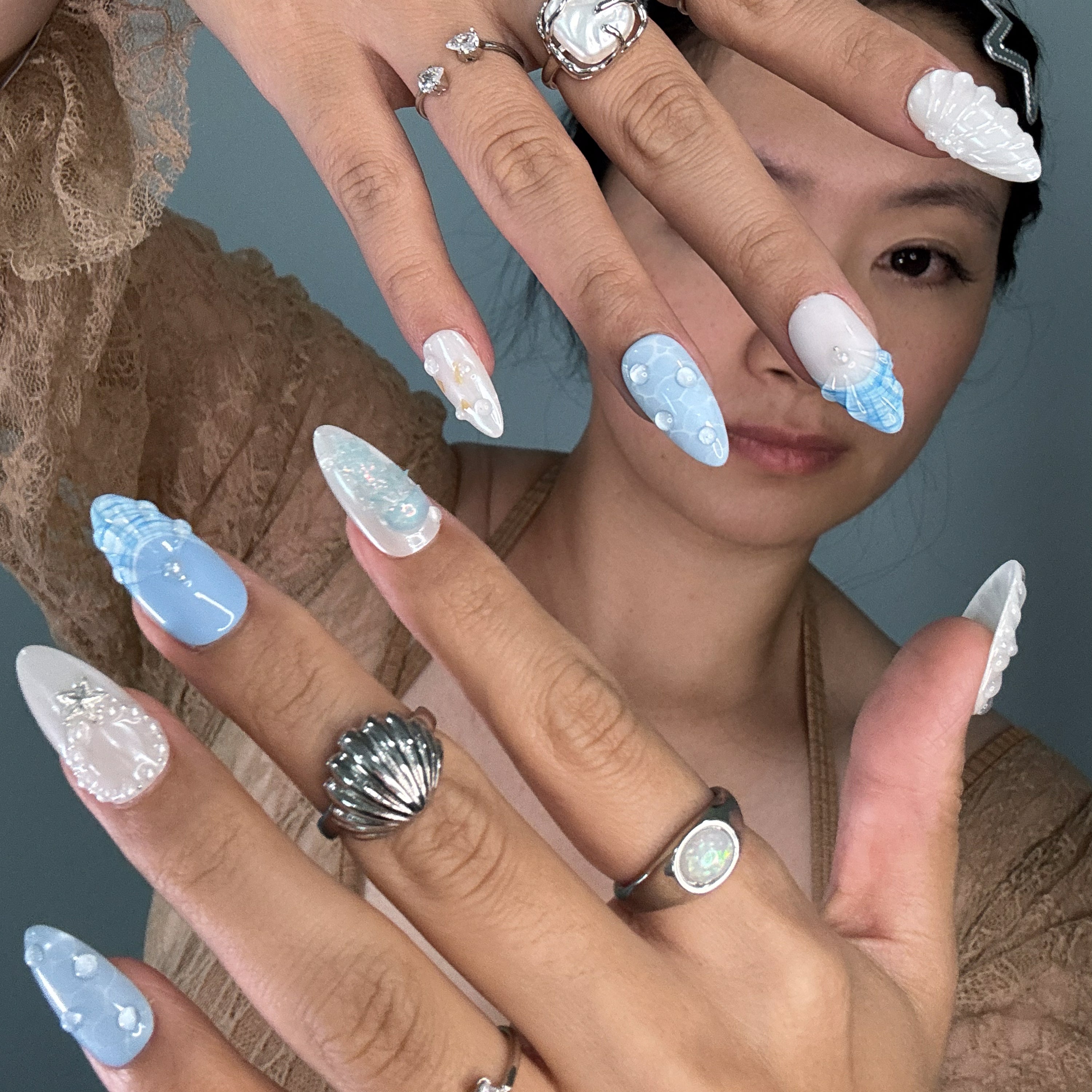 Coastal Color Story: Cool pastel blues and creamy pearls bring breezy, beachy elegance.
• Sculpted Sea Motifs: 3D jellyfish, starfish, and shell ridges turn each nail into a tiny seascape.
• Iridescent Glow: Opal shimmer and pearl accents mimic the glisten of sea foam and sunlight on water.
• Unique Ocean Textures: Bubble effects, netting patterns, and wave-like lines evoke the depth of the deep sea.
• Almond Shape: Sleek and feminine, perfect for balancing oceanic whimsy with everyday wear.