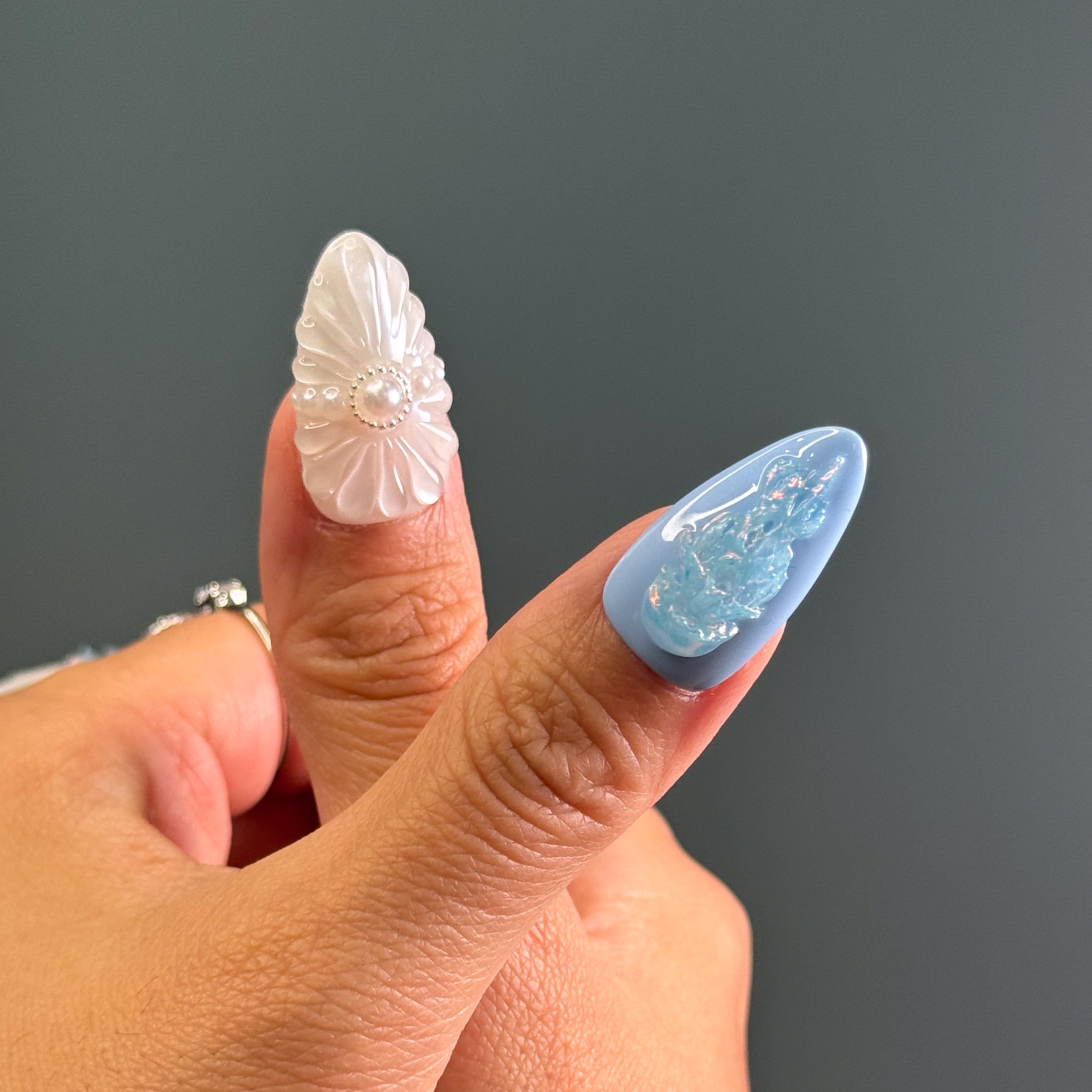 Coastal Color Story: Cool pastel blues and creamy pearls bring breezy, beachy elegance.
• Sculpted Sea Motifs: 3D jellyfish, starfish, and shell ridges turn each nail into a tiny seascape.
• Iridescent Glow: Opal shimmer and pearl accents mimic the glisten of sea foam and sunlight on water.
• Unique Ocean Textures: Bubble effects, netting patterns, and wave-like lines evoke the depth of the deep sea.
• Almond Shape: Sleek and feminine, perfect for balancing oceanic whimsy with everyday wear.