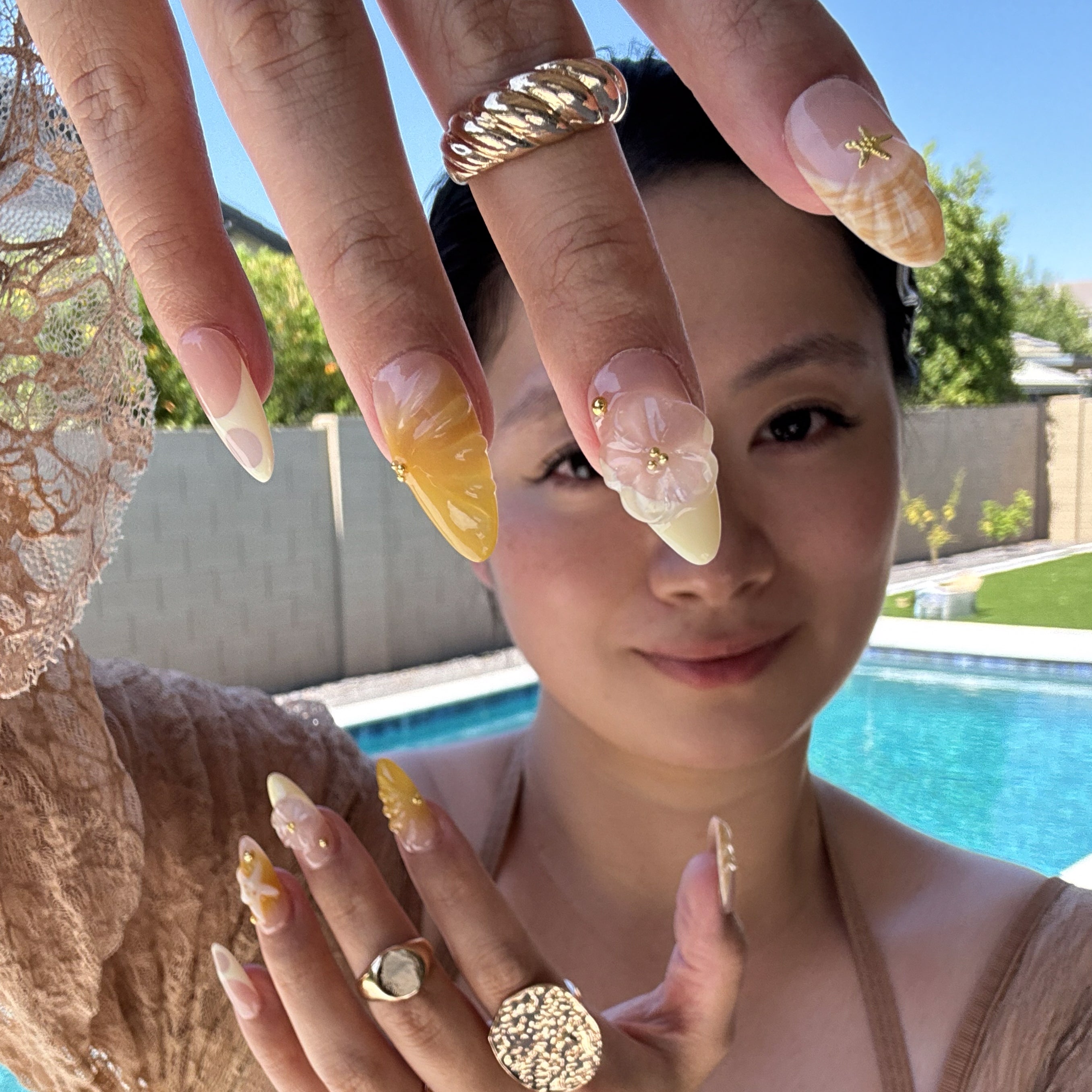 Coastal Color Palette: Taupe, honey yellow, ivory cream, and shell-inspired swirls for that sun-bleached vibe.
• 3D Starfish & Flowers: Hand-sculpted ocean motifs bring depth and summer romance to each nail.
• Textured Shell Accents: Wave-like and seashell textures evoke the feeling of walking barefoot on warm sand.
• Gold Bead Embellishments: Delicate studs and tiny stars add a glimmer of ocean treasure.
• Almond Shape: Natural, beachy elegance with a soft tapered point perfect for sunny adventures.