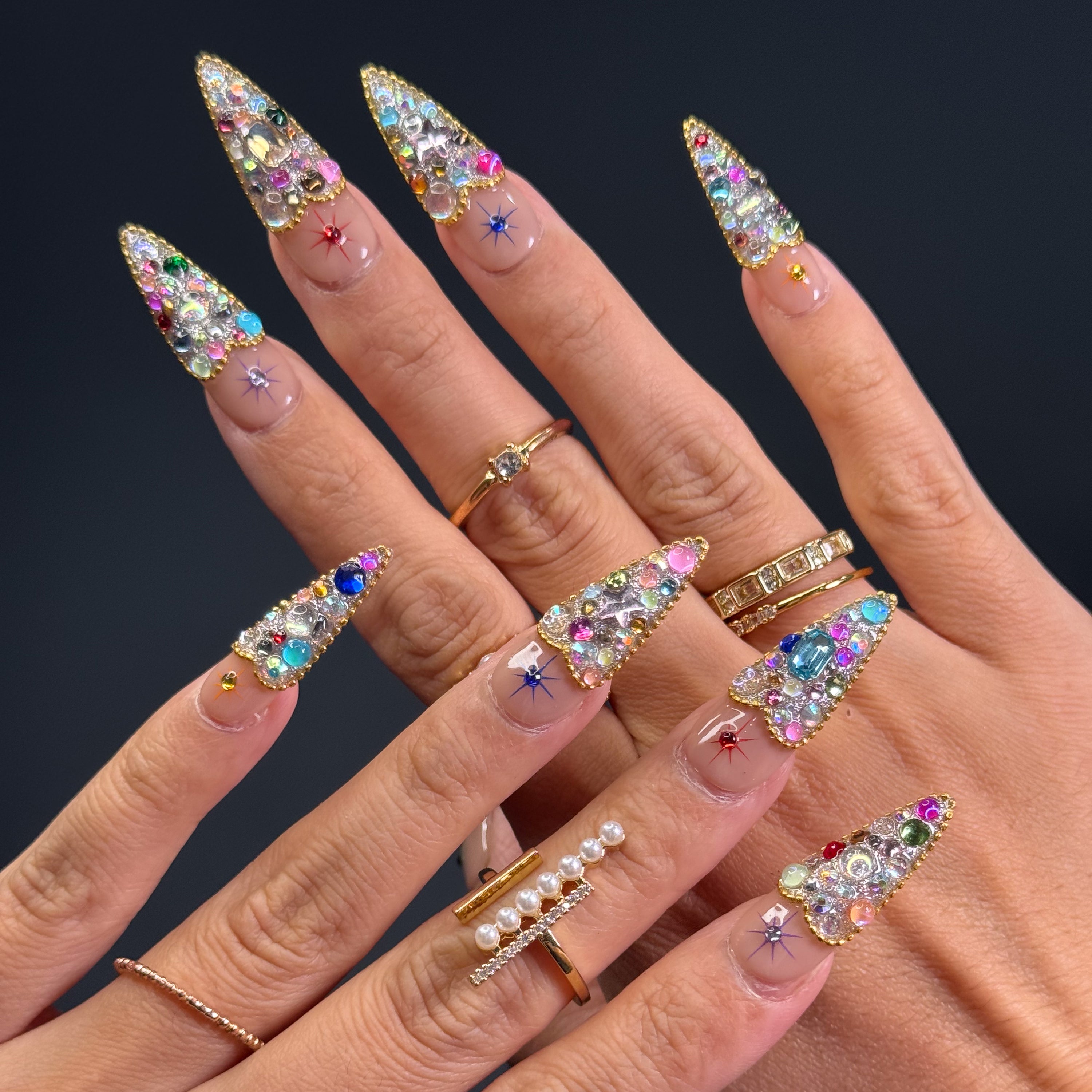 Full Gem Explosion: Packed with multicolored rhinestones, glass crystals, and faceted jewels for instant glam.
• Golden Glitter Base: A bold, sparkling foundation gives each nail the weight of a red carpet moment.
• Starburst Charms: Embedded celestial motifs add a magical pop to every fingertip.
• Luxe Color Palette: Emerald, sapphire, ruby, and amethyst tones blend for a jewel box effect.
• Short Tapered Shape: Compact yet eye-catching—perfect for glam lovers who want comfort and drama.