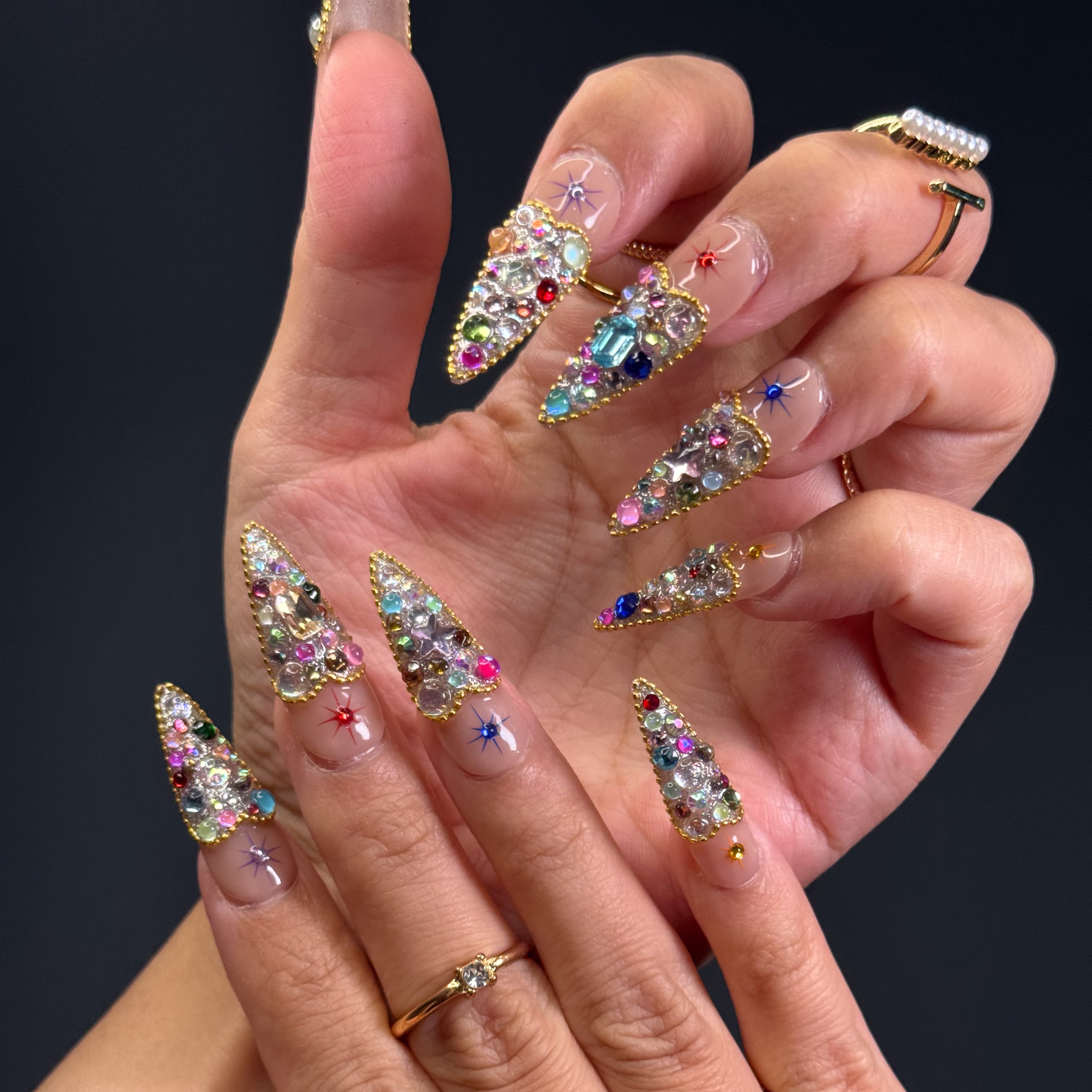 Full Gem Explosion: Packed with multicolored rhinestones, glass crystals, and faceted jewels for instant glam.
• Golden Glitter Base: A bold, sparkling foundation gives each nail the weight of a red carpet moment.
• Starburst Charms: Embedded celestial motifs add a magical pop to every fingertip.
• Luxe Color Palette: Emerald, sapphire, ruby, and amethyst tones blend for a jewel box effect.
• Short Tapered Shape: Compact yet eye-catching—perfect for glam lovers who want comfort and drama.