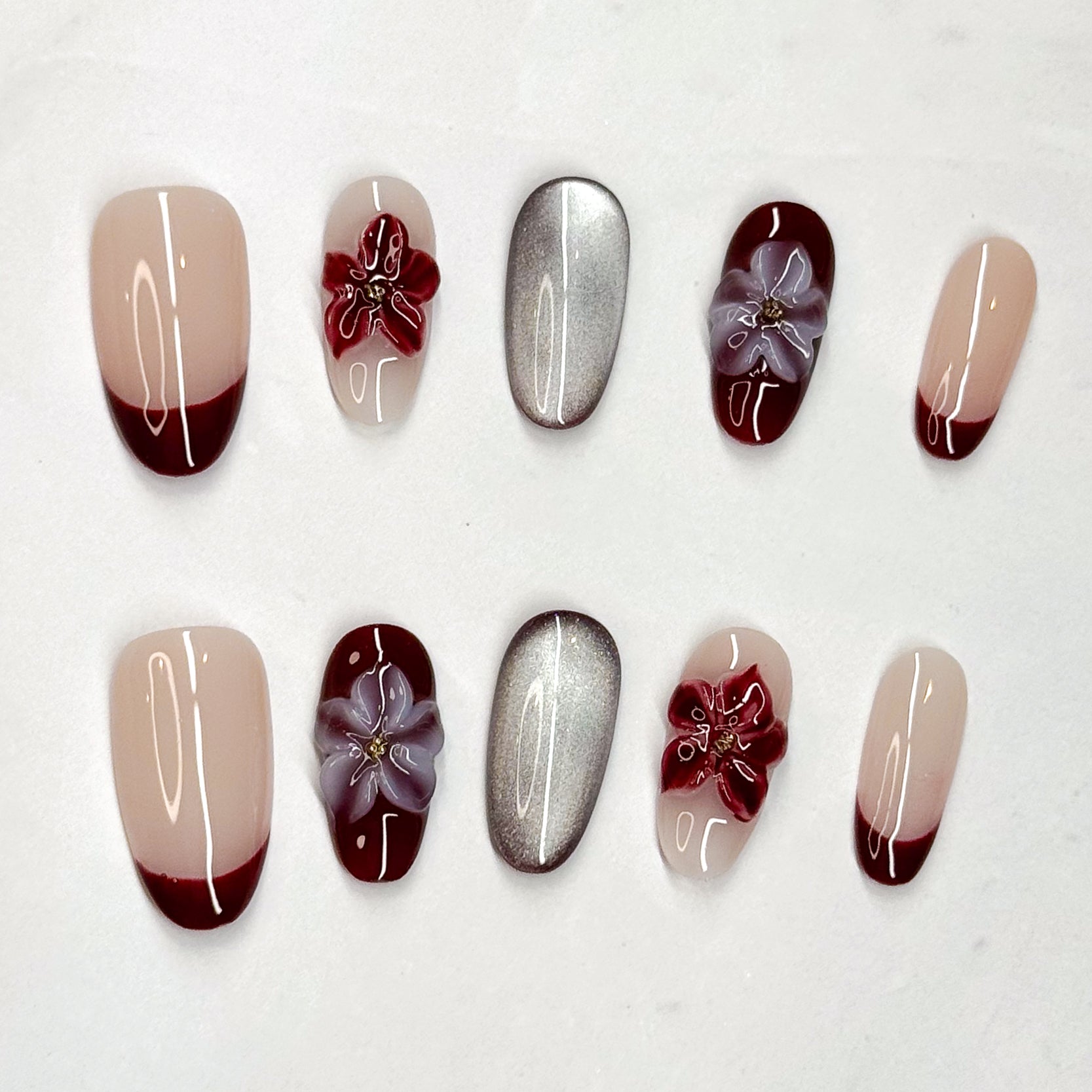 • Rich Contrast: Wine red French tips paired with nude bases for a chic finish.
• Metallic Accent: Mirror-like silver nails for a modern luxe edge.
• 3D Florals: Handcrafted gel flowers in crimson and lilac for depth and charm.
• Almond Shape: Elongates the fingers while staying feminine and refined.
• Handmade & Reusable: Durable, salon-quality design made with care.