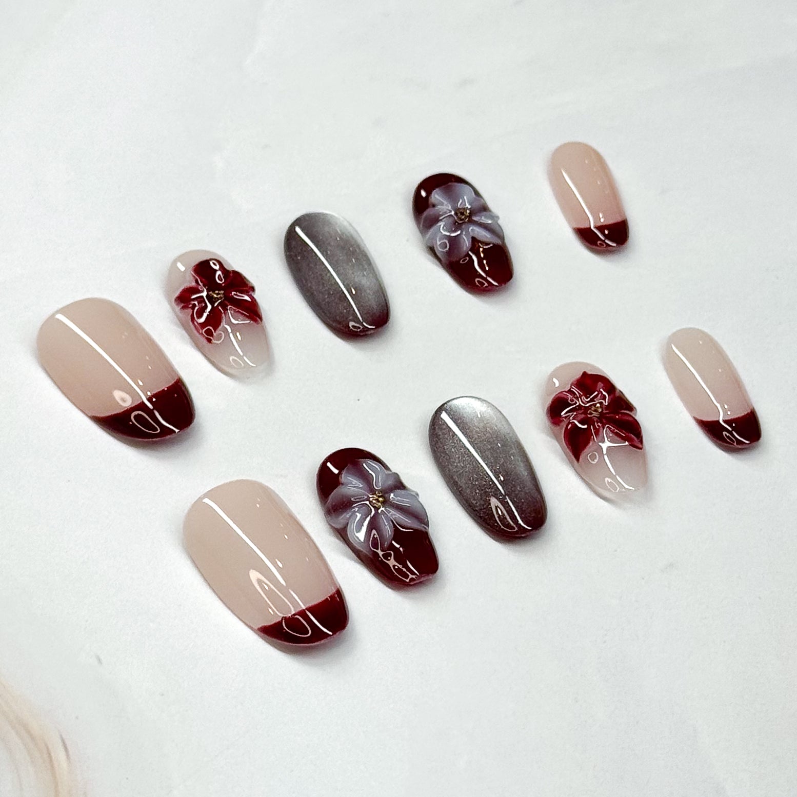 • Rich Contrast: Wine red French tips paired with nude bases for a chic finish.
• Metallic Accent: Mirror-like silver nails for a modern luxe edge.
• 3D Florals: Handcrafted gel flowers in crimson and lilac for depth and charm.
• Almond Shape: Elongates the fingers while staying feminine and refined.
• Handmade & Reusable: Durable, salon-quality design made with care.